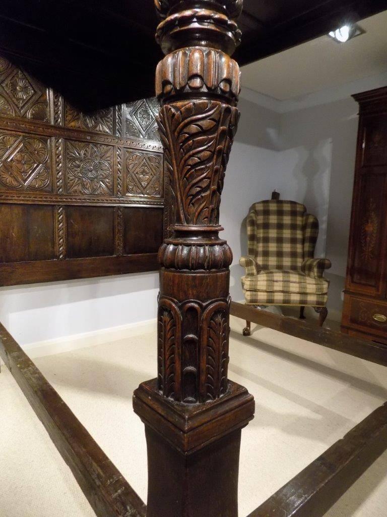 A magnificent oak Elizabethan Revival four-poster bed king-size bed. Having a panelled canopy with finely carved moulding and frieze, supported on turned and carved balustrade columns to the base. Having flat carved posts to the headboard with