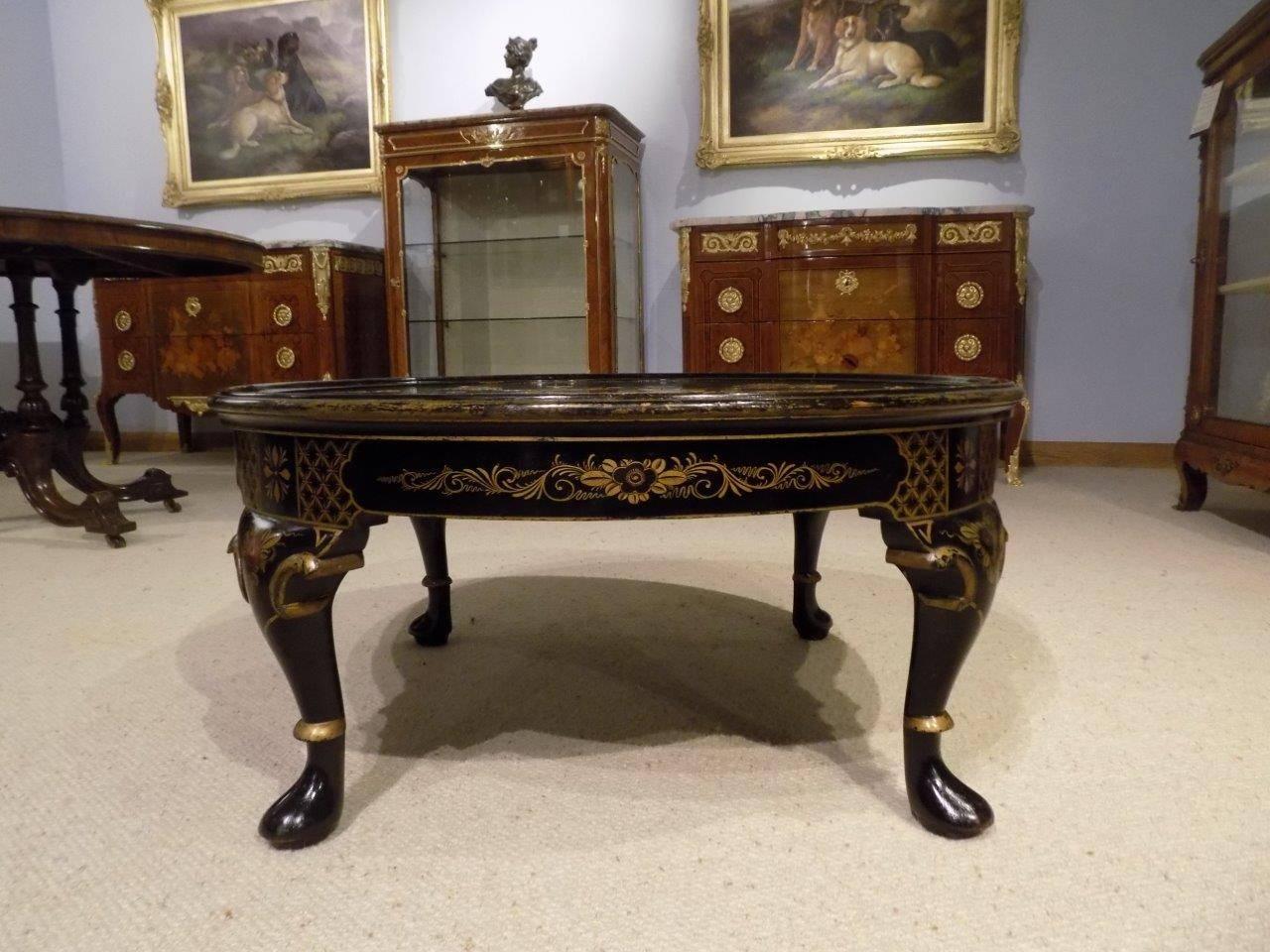 A 1920s period chinoiserie lacquered antique coffee table. Having a circular dished top with raised gold and polychrome lacquer detail depicting an oriental landscape with a gilded border and supported on short cabriole legs with pad feet with