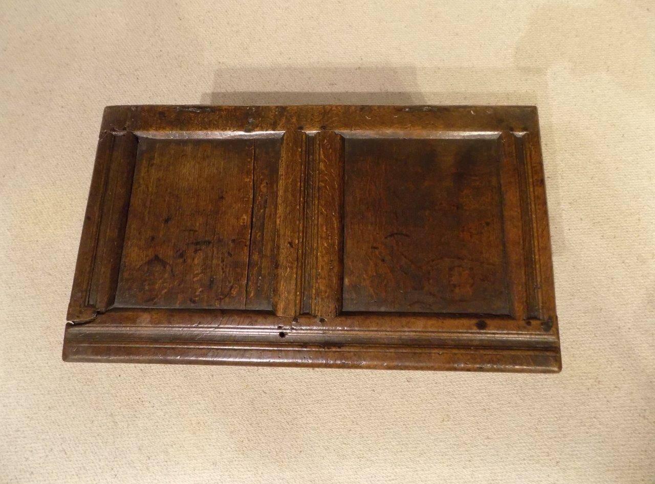 A rare small oak 17th century two-panel coffer. The hinged top with two panels and retaining the original split pin hinges, opening to reveal a candle box with a carved front, steel lock plate, panelled ends and back and supported on the original