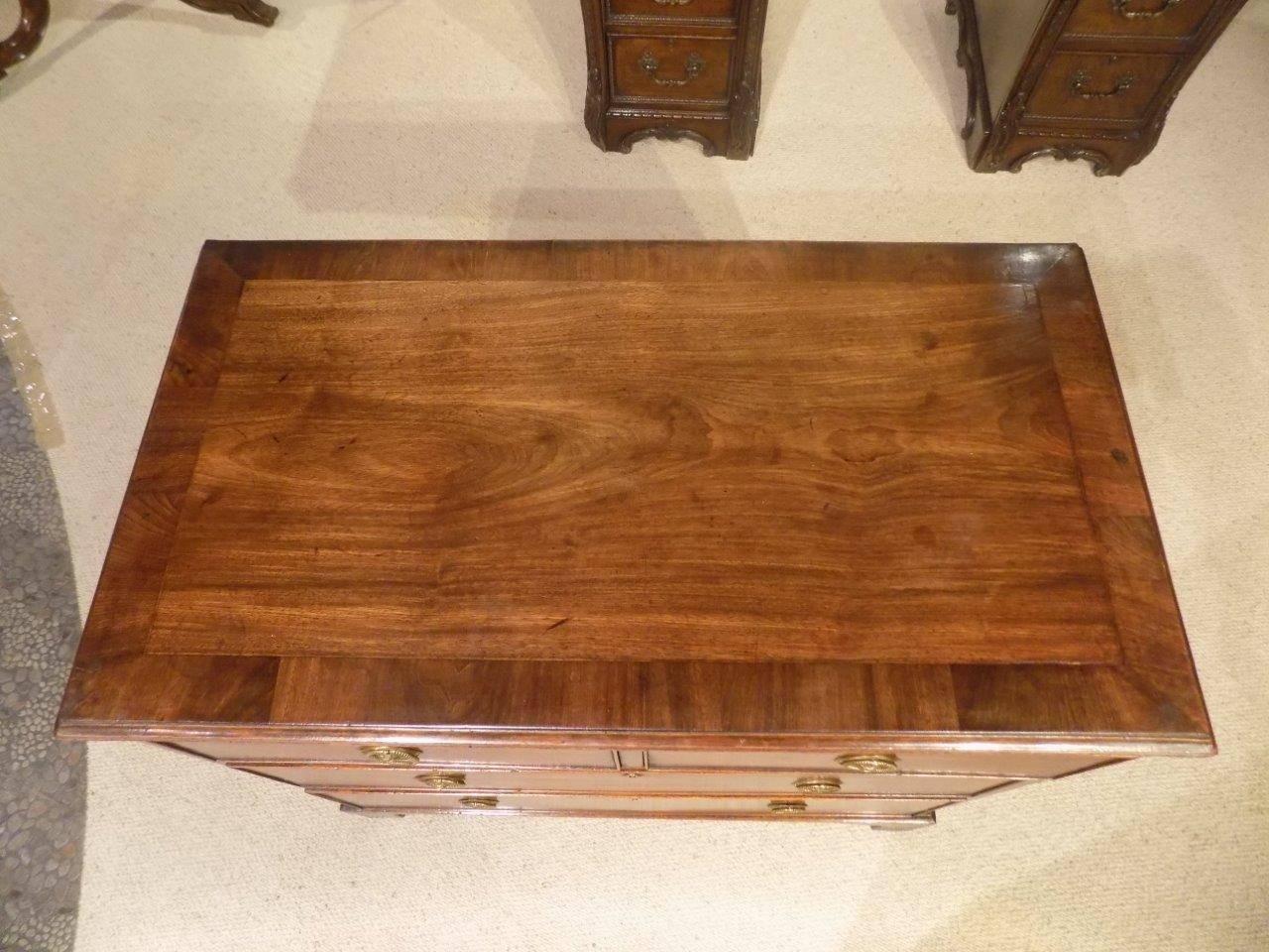 A small mahogany and oak Regency Period antique chest of drawers. The rectangular top in beautifully figured mahogany with mahogany crossbanding, above an arrangement of two short and two long rectangular oak lined drawers with the original circular