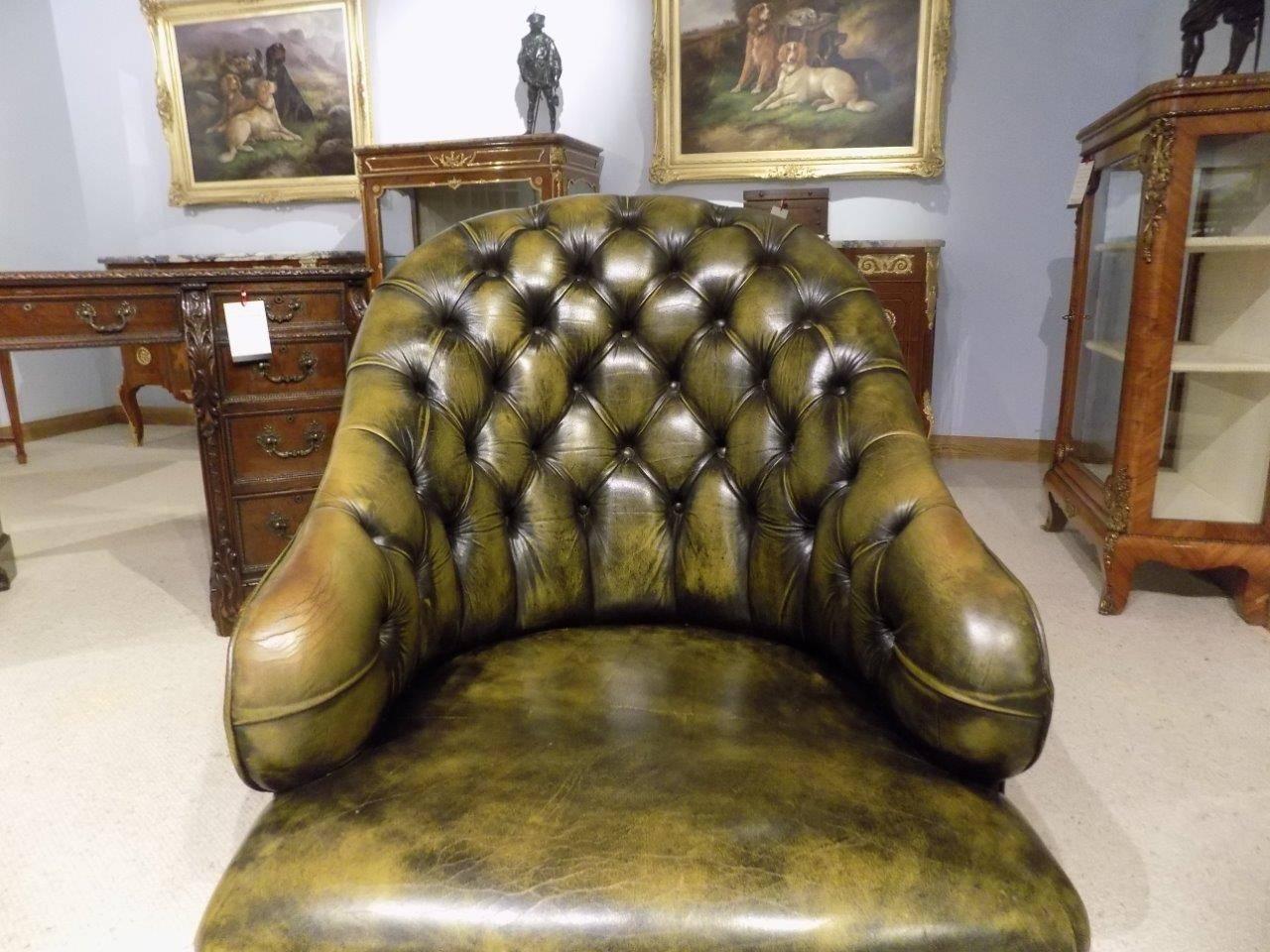 A green leather deep buttoned Victorian period antique Tub chair. Having a shaped back with deep buttoned upholstery and a generous leather seat with brass studded detail. Supported on turned front, mahogany supports with brass castors and splayed