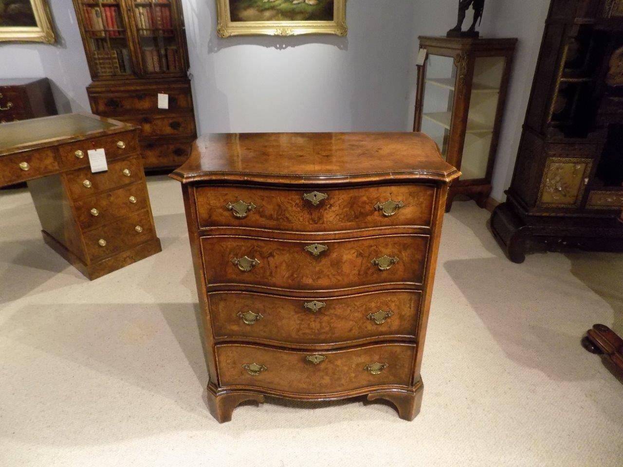 A burr walnut George II style burr serpentine chest of drawers. The top of serpentine outline being veneered in richly figured burr walnut with herringbone and walnut banding and a block moulded edge. The four graduating serpentine shaped drawers