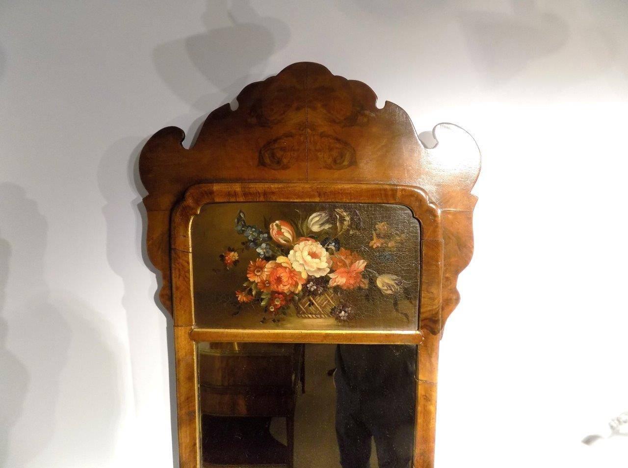 A small walnut Queen Anne style wall mirror. Having a shaped crest veneered in burr walnut above a still life oil painting and rectangular mirror within a walnut frame, English, circa 1900

Dimensions: 33