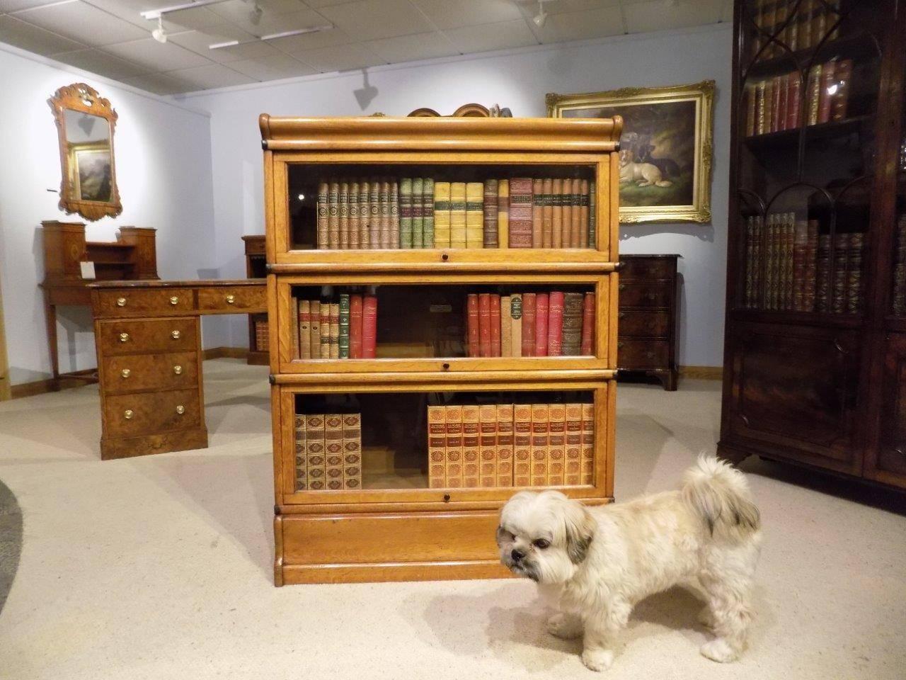 An oak Edwardian three stacking bookcase by Globe Wernicke. The solid oak moulded cornice above three hinged glazed doors with brass knobs and copper strapped sides. Supported on a solid oak plinth base, English, circa 1900-1910

Dimensions: 45