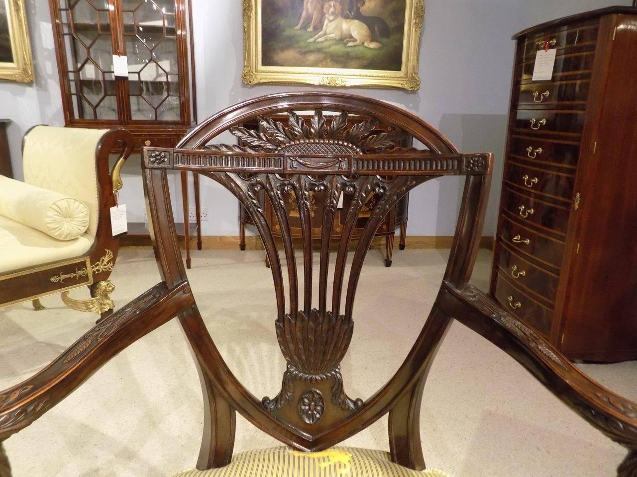 A fine quality mahogany Hepplewhite style carved antique armchair. The shield shaped back with finely carved pierced splat, having open swept arms, with fine acanthus leaf carvings. Raised on reeded front supports and swept rear supports.