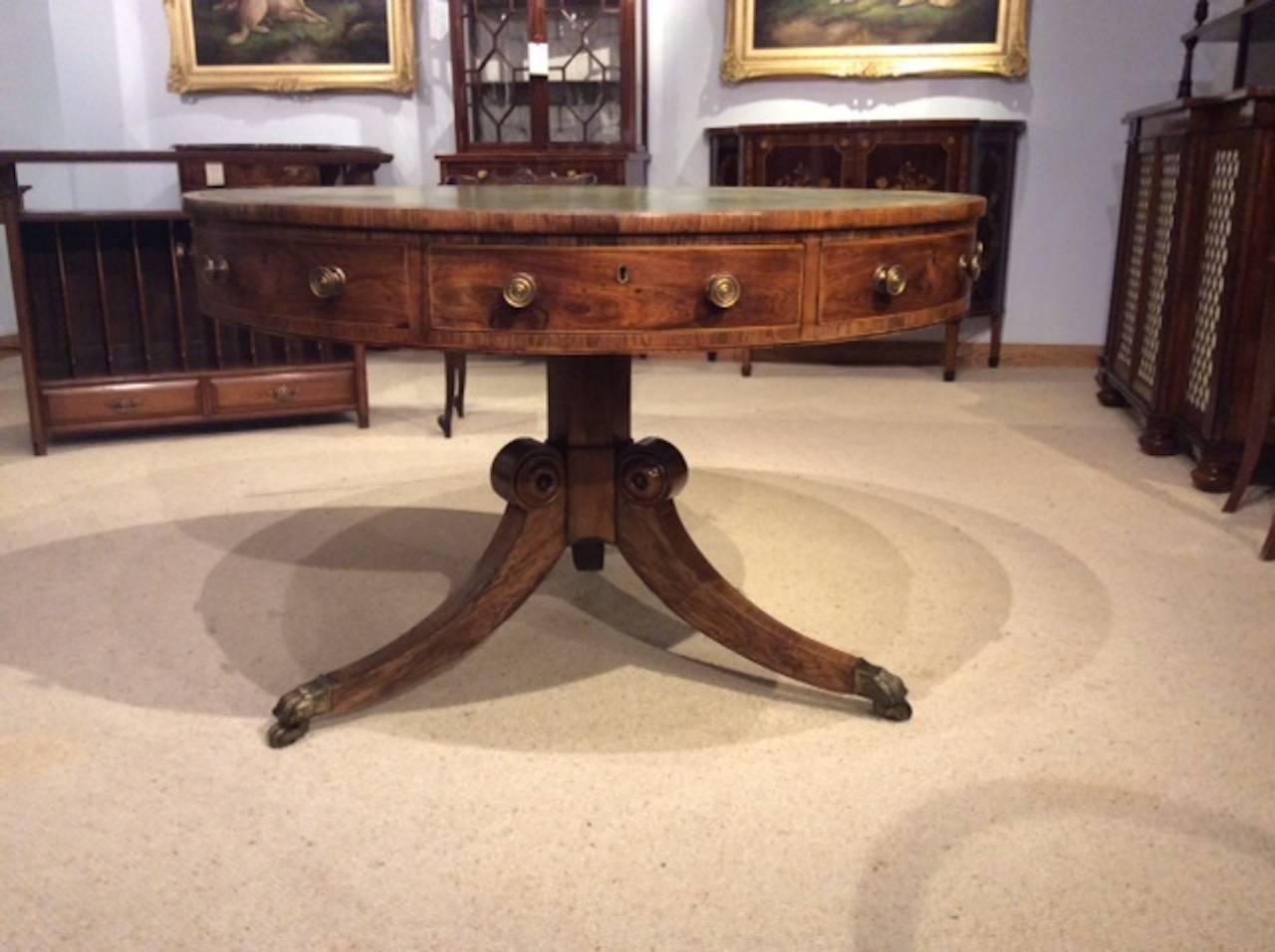 A good rosewood Regency period antique revolving drum table. Having a circular top with a pale green circular leather insert with gilt tooling and cross banded in rosewood. The frieze with four cedar lined drawers and four compartments with circular