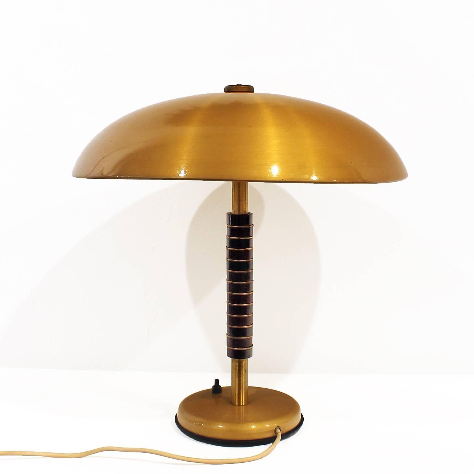 Desk lamp, stand with wood pieces alternated with polished brass rings, brass lampshade.

Belgium, circa 1950.