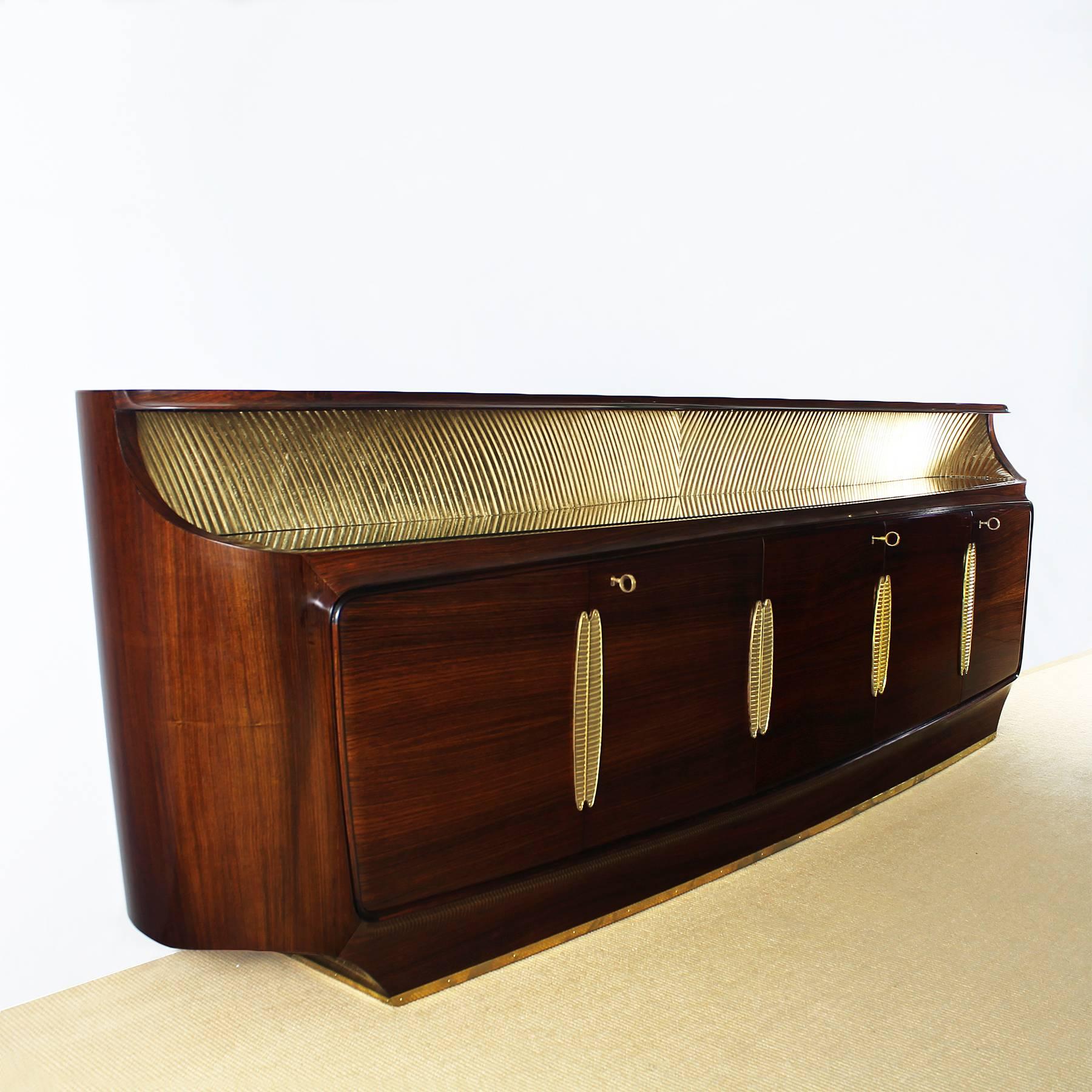 Spectacular rounded sideboard, high cabinet-making quality, rosewood veneer, French polish, five doors, the four side ones with shelves and the middle one with drawers, ivory lacquered wood inside. Decorative undulant gold leaf panel and original