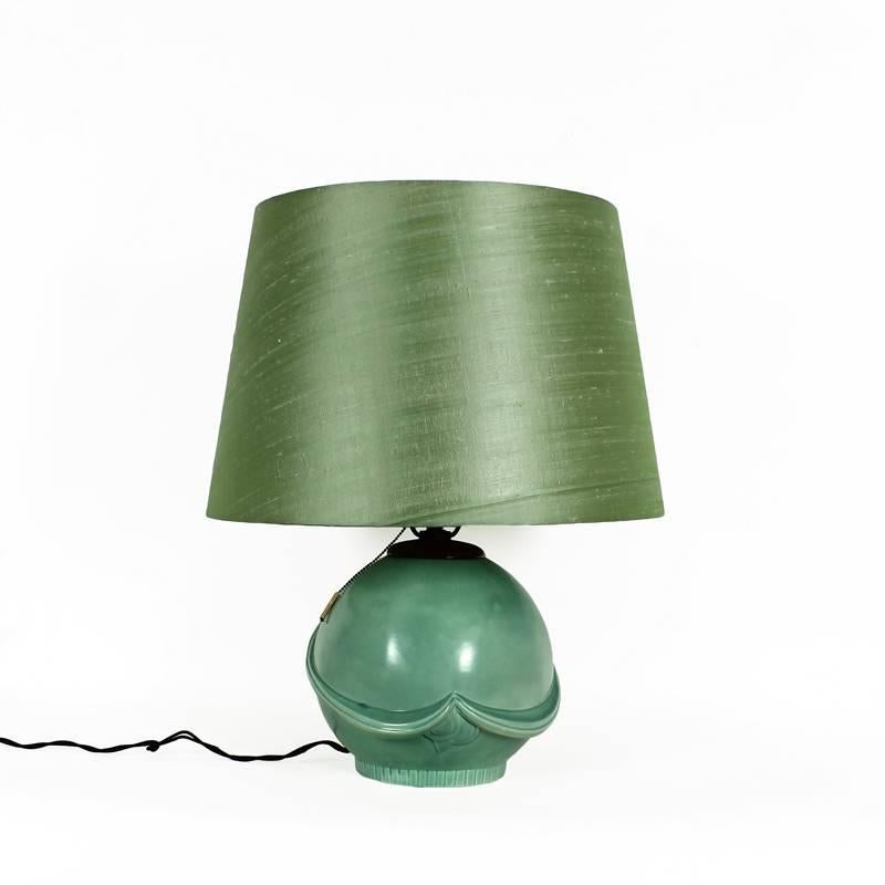 Art Deco table lamp, celadon green ceramic, ingenius wood light support, almond green silk lampshade. Many marks and stamps at the base.

Czechoslovakia, circa 1930.