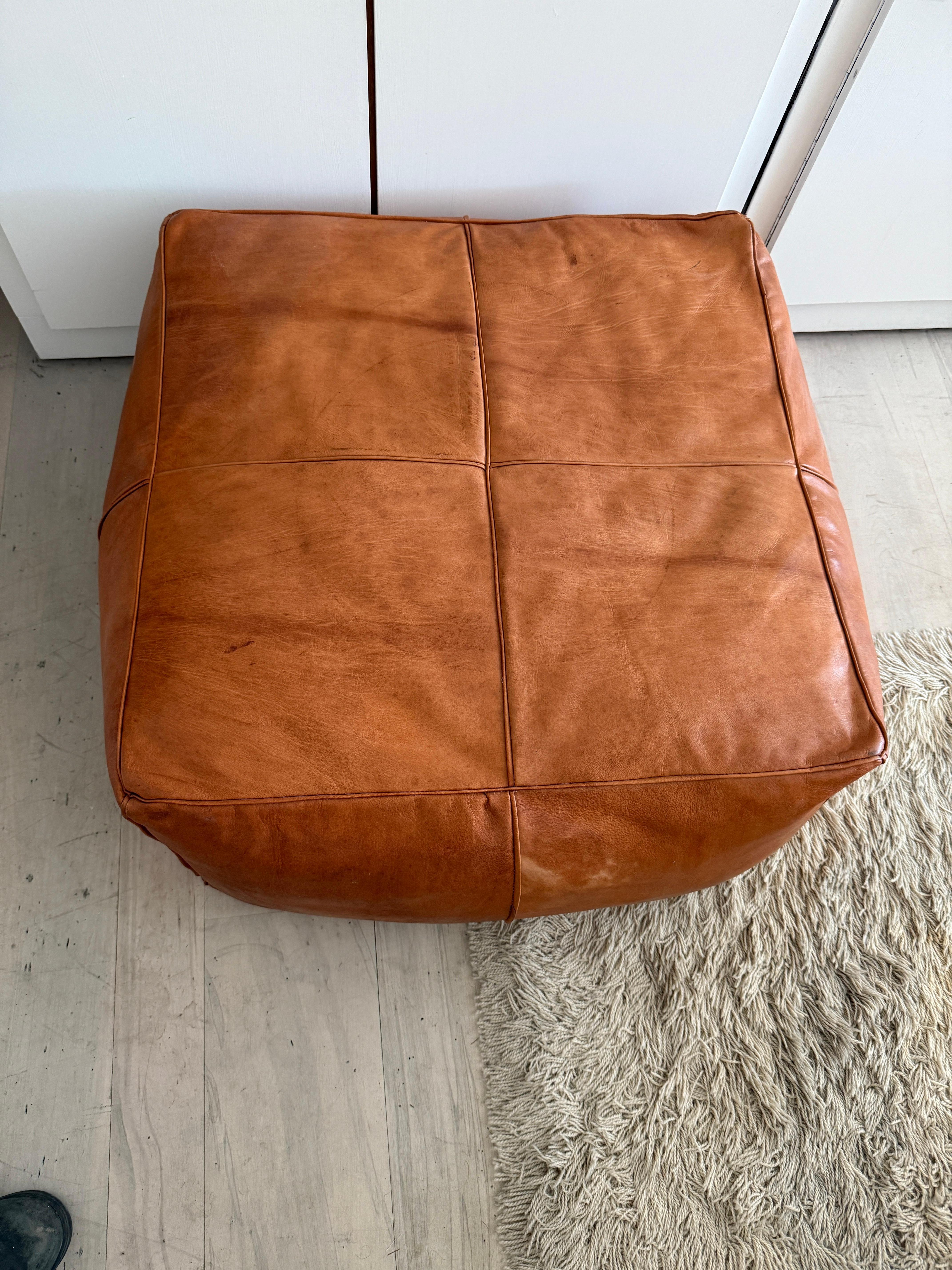 Vintage leather square pouf or ottoman In the style of De Sede. Nice heavy square cognac brown leather. High quality leather and great stitching. Dense feel very comfortable has nice patina some marks and stains but presents well.

Measures 38”