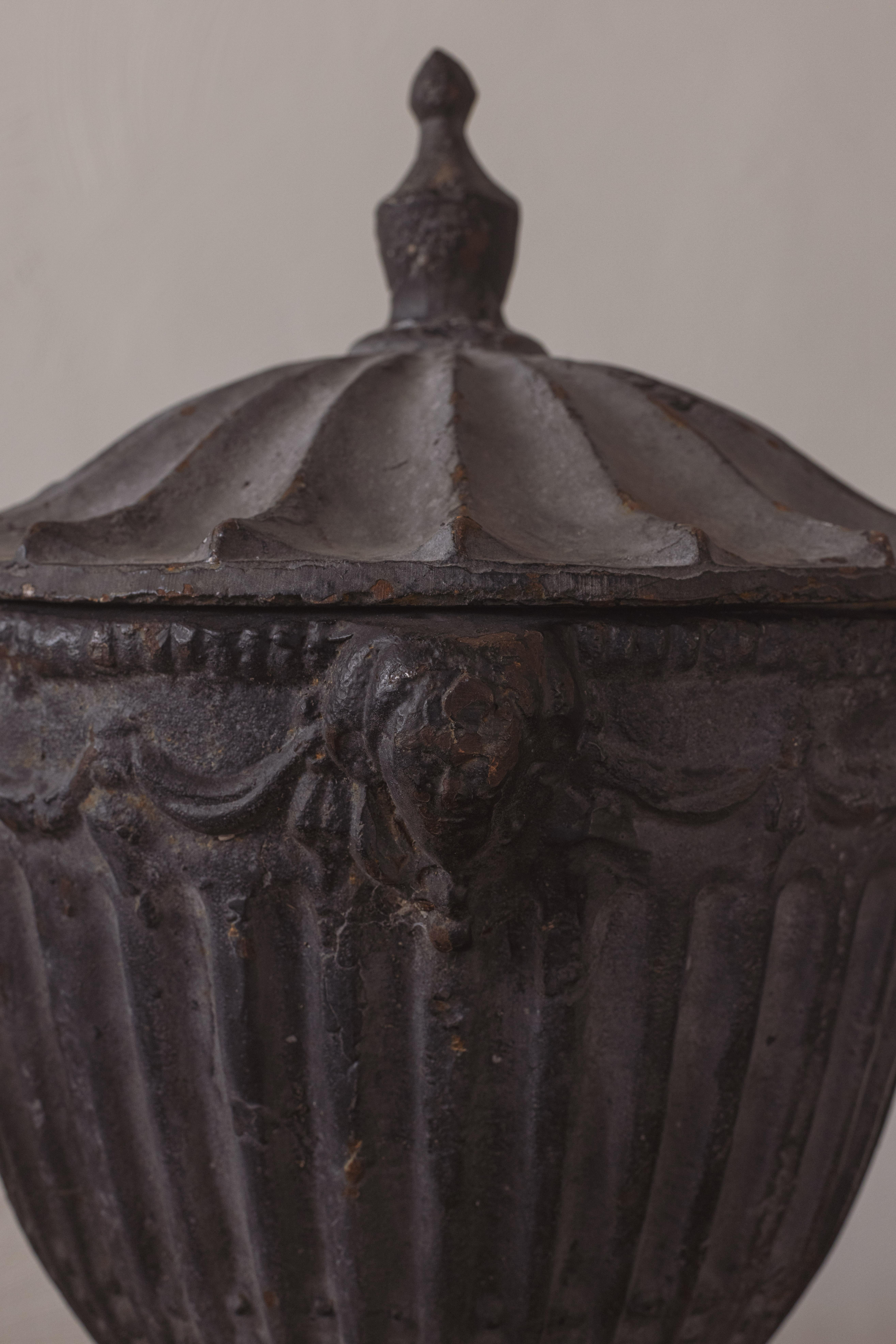 A pair of painted cast iron neoclassical urns with fluted bodies, swag decoration and domed lids. To be displayed inside or in the garden. Wonderful condition. 

England, 1910