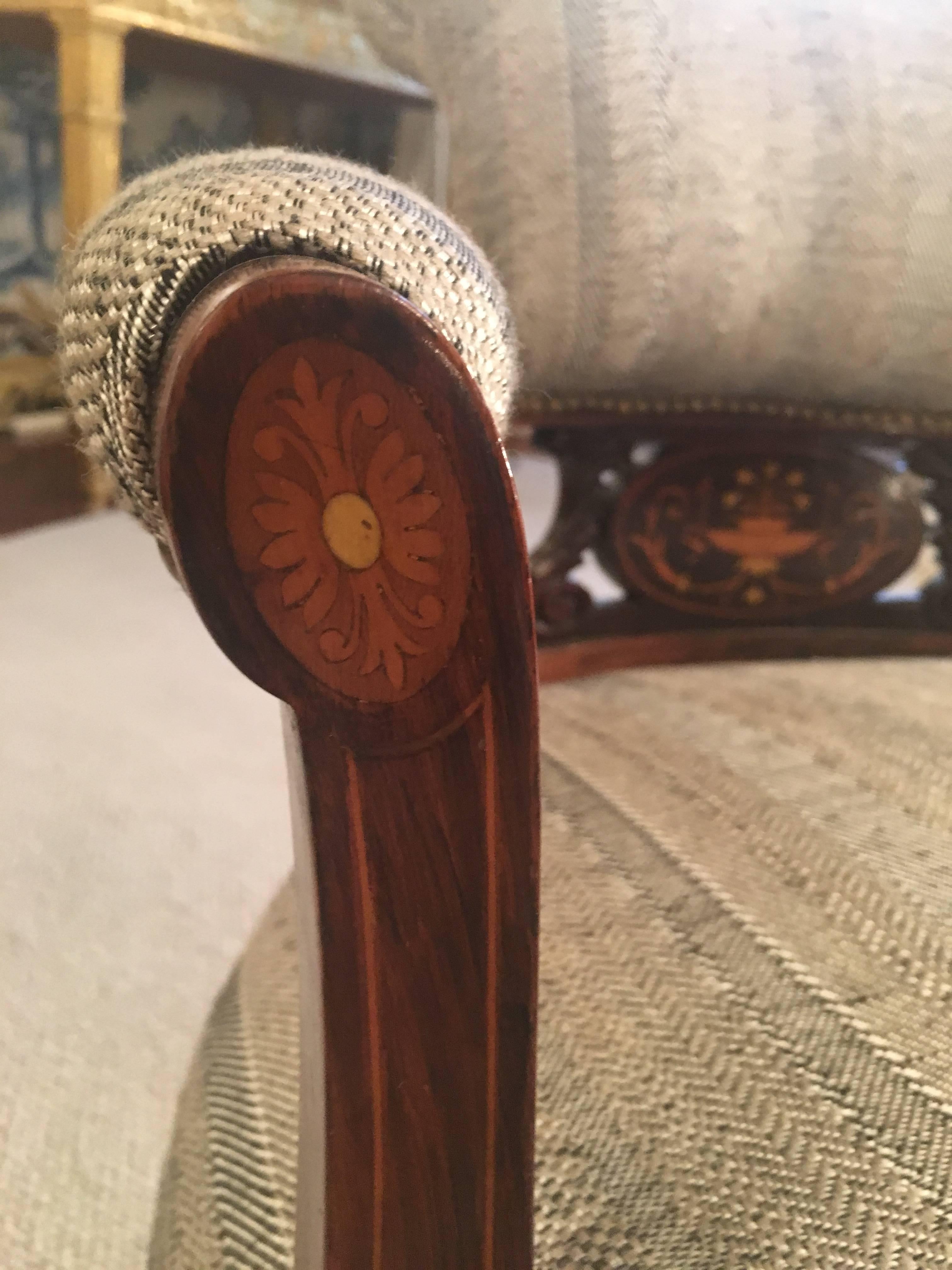 The pair of rosewood tub chairs have a central inlaid medallion with floral motifs. 
The two front legs on castors. 
The upholstery is new.