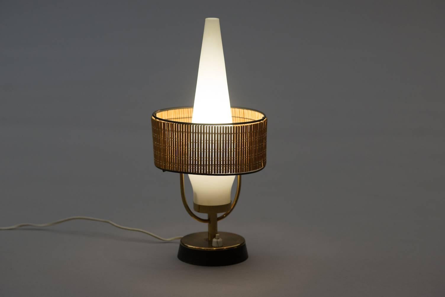 Table lamp with a straw and frosted glass shade, base in brass and black painted metal.