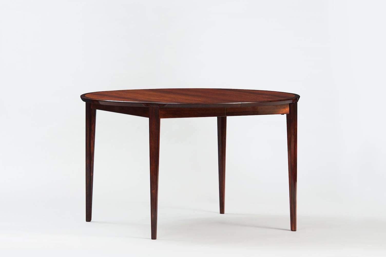 Rosewood extendible dining table with two leaves, one of the leaves folds into the inside of the table.
