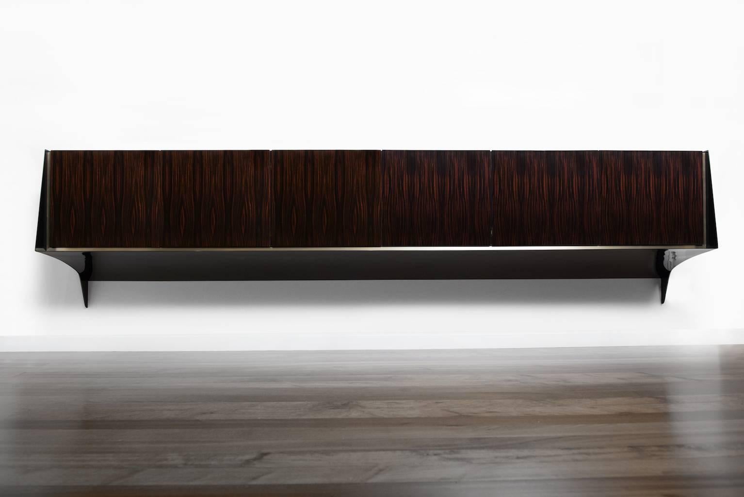 Shown in French polished Macassar ebony and black lacquer, with sycamore interior. The base of the sideboard is not parallel to the floor but curved towards the wall. 
The Keel credenza by Pipim is customizable to any dimension and is available in a