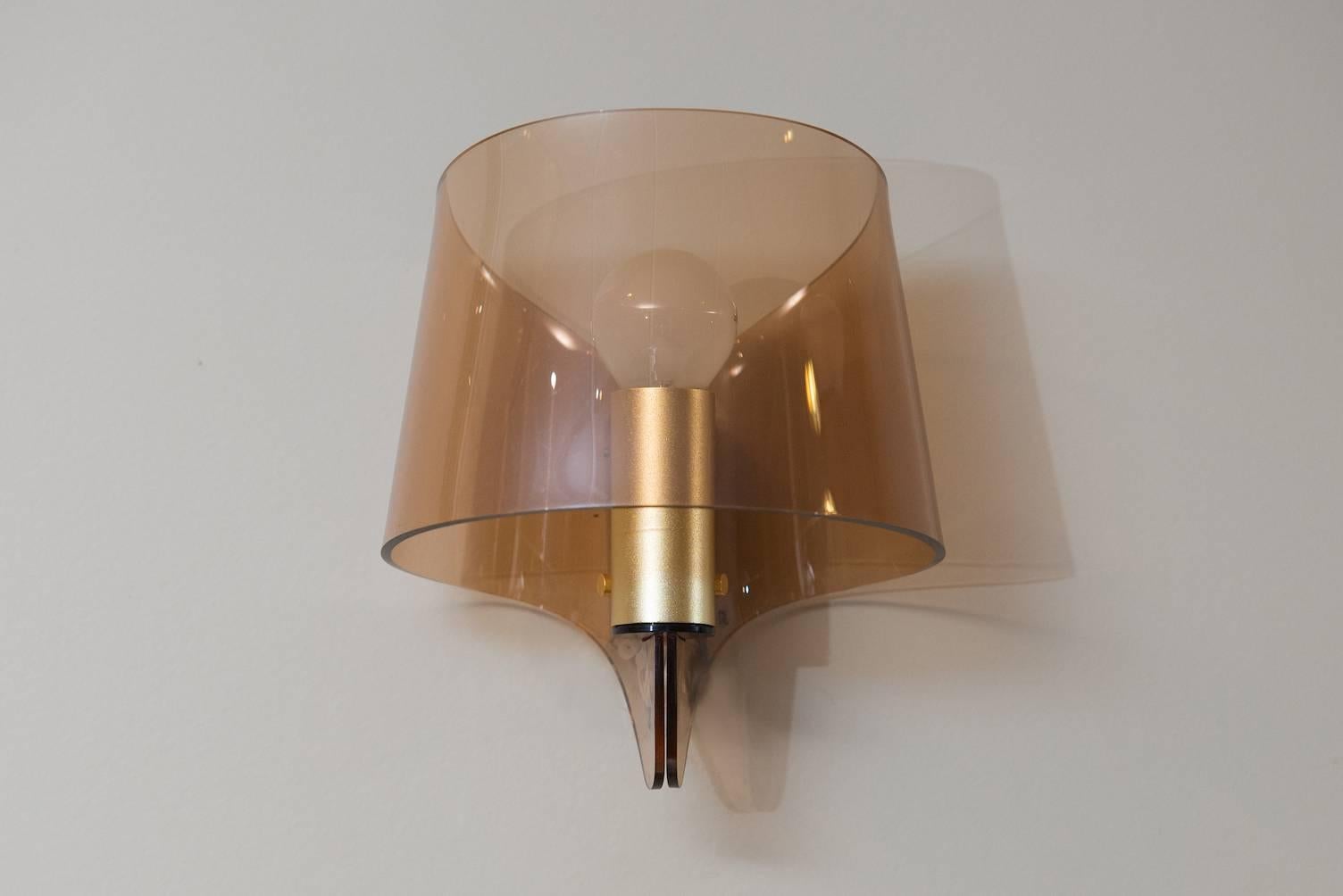 A pair of wall sconces in brass and smoked plexiglass.