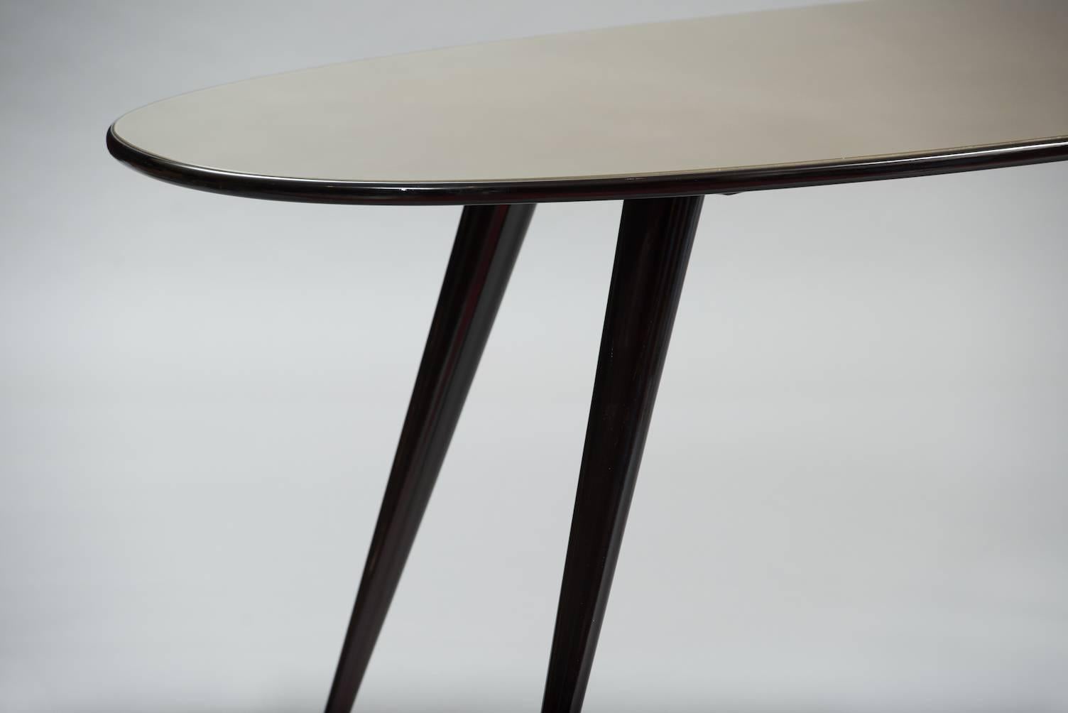 Ebonized wood oval dining table with a glass lacquered top.