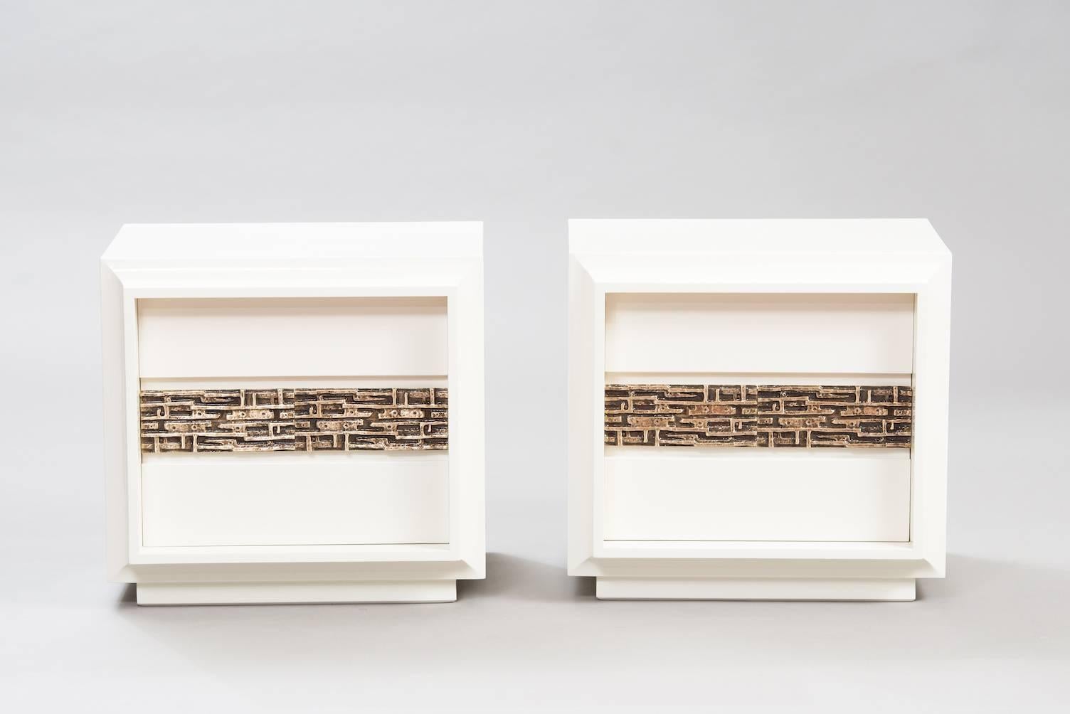 Ivory lacquered pair of nightstands with trademark bronze detailing.