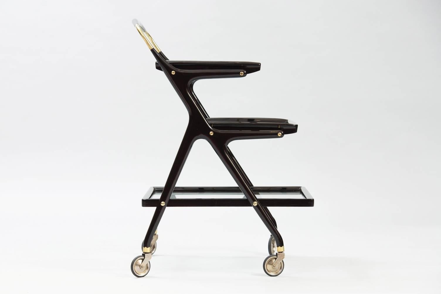 Three-tier rolling cart in ebonized wood, brass and glass with two removable trays.