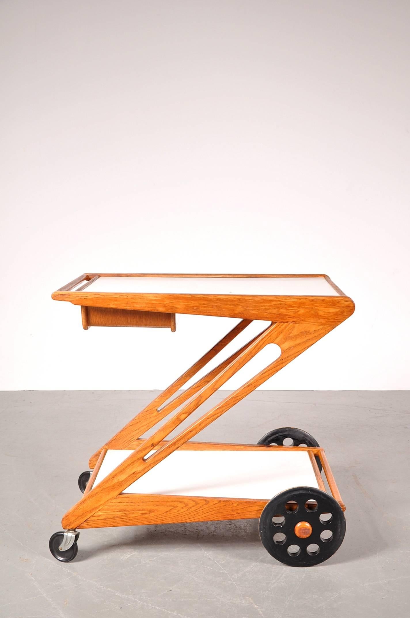 Extreamly rare trolley designed by Cees Braakman, manufactured by Pastoe in the Netherlands, circa 1950.

This unique piece has a oak wooden Z-shaped base with white laminated tops and black wooden weels. The upper top can slide open, revealing a