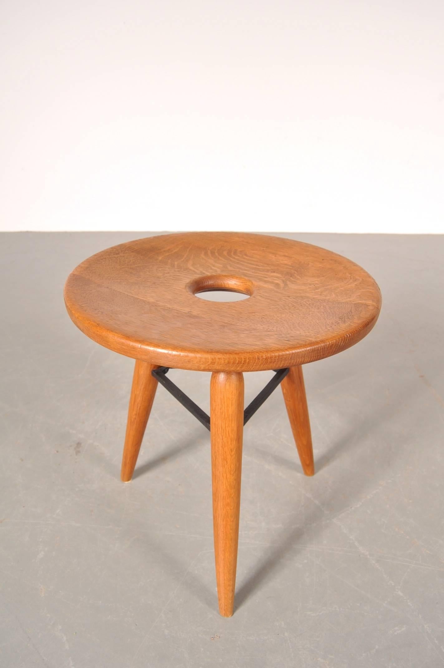 Beautiful wooden tripod stool, manufactured in France, circa 1950.

This unique piece is made of oak wood with cast iron supports. The round seat has a perforated hole in the middle, all together giving this wonderful piece an eye-catching