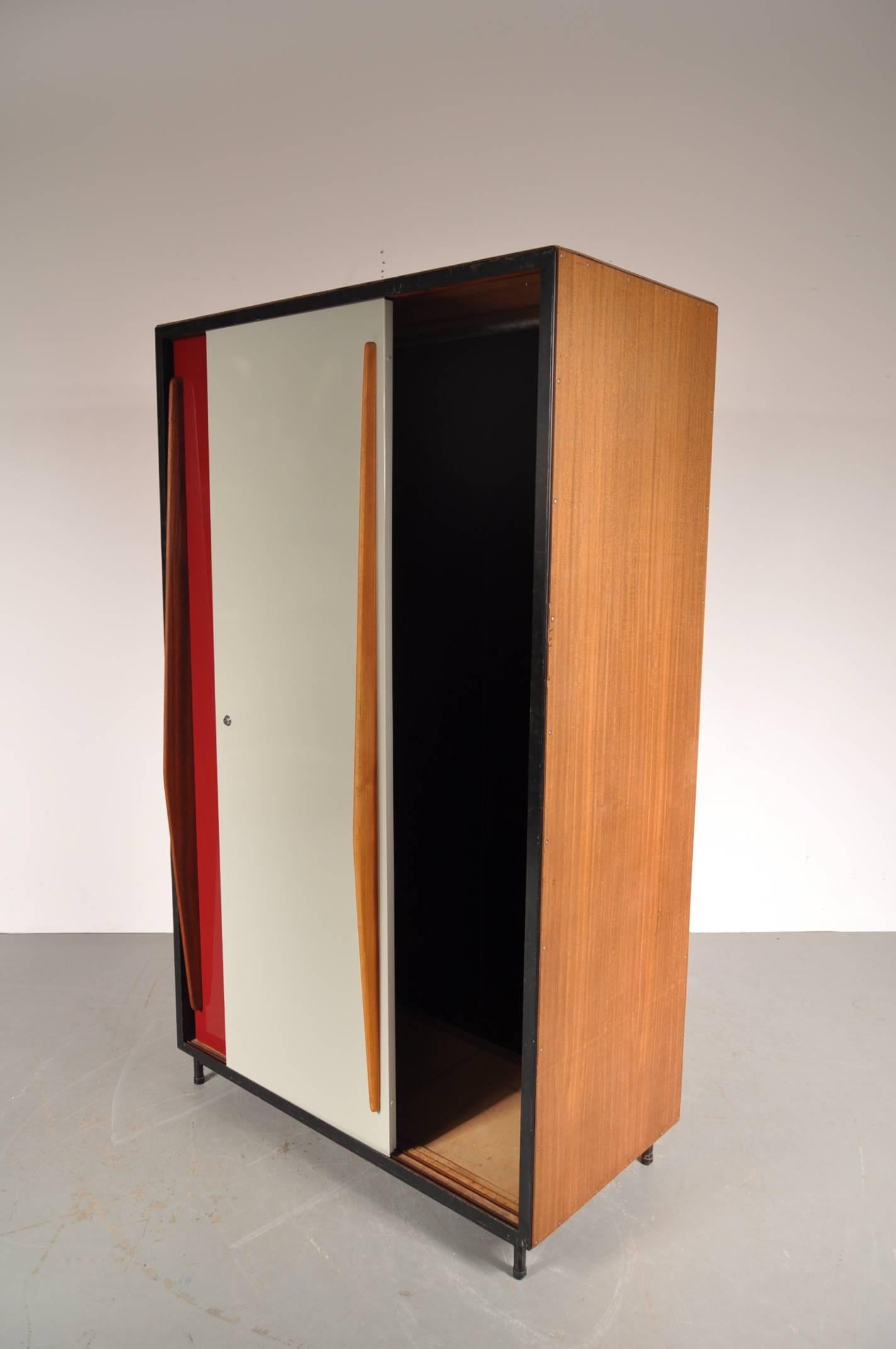 Amazing wardrobe designed by Willy Van Der Meeren, manufactured by Tubax in Belgium in 1952.

This eye-catching piece is made of beautiful quality wood on a black metal structure. The most unique features are the red and white metal sliding doors