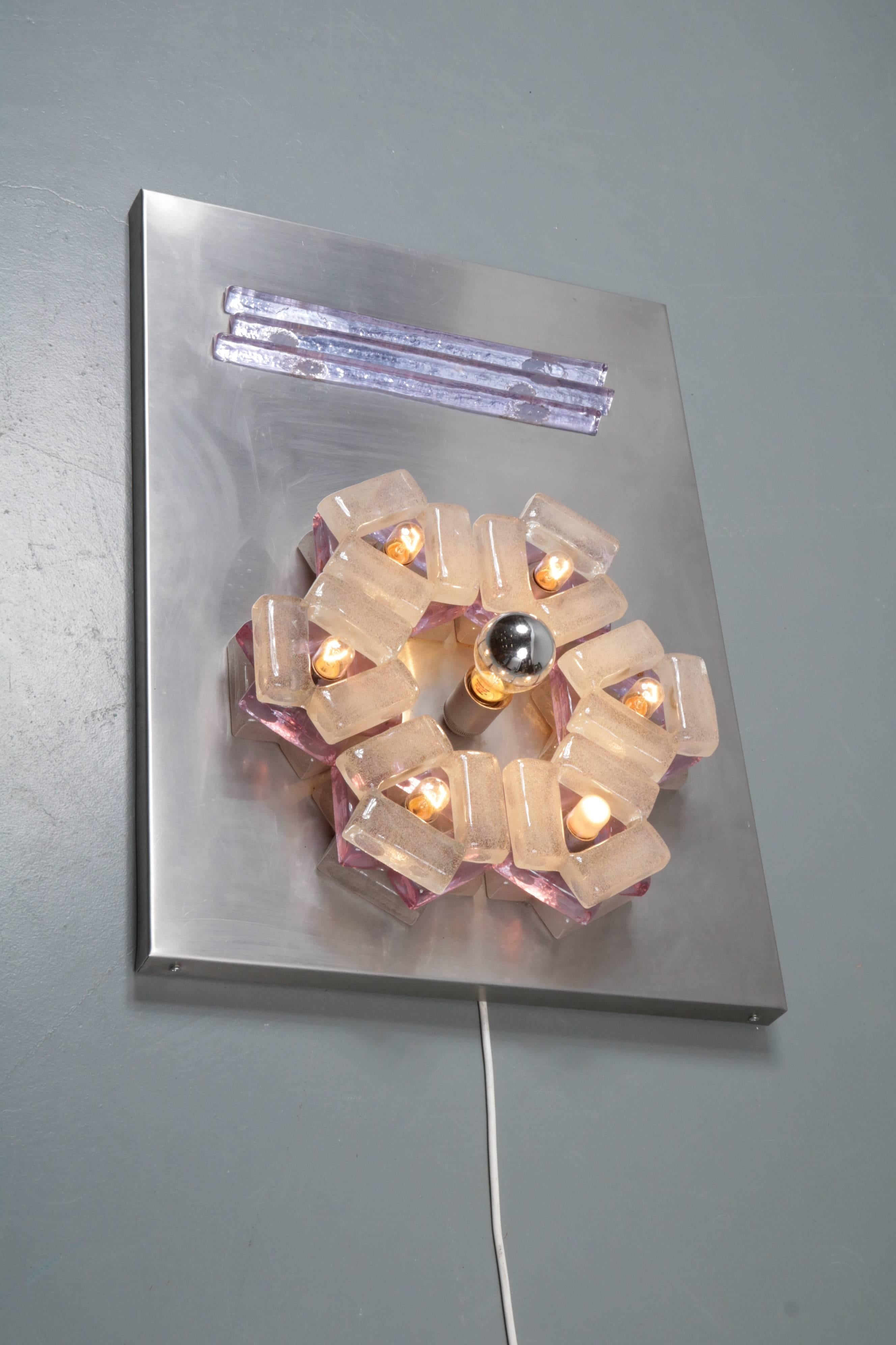 An eye-catching large sculptural wall light manufactured by Poliarte in Italy in the 1960s.

This rare lamp is made of a metal plate holding pieces of glass in different shapes and colors, giving it the eye-catching artistic style that Poliarte is