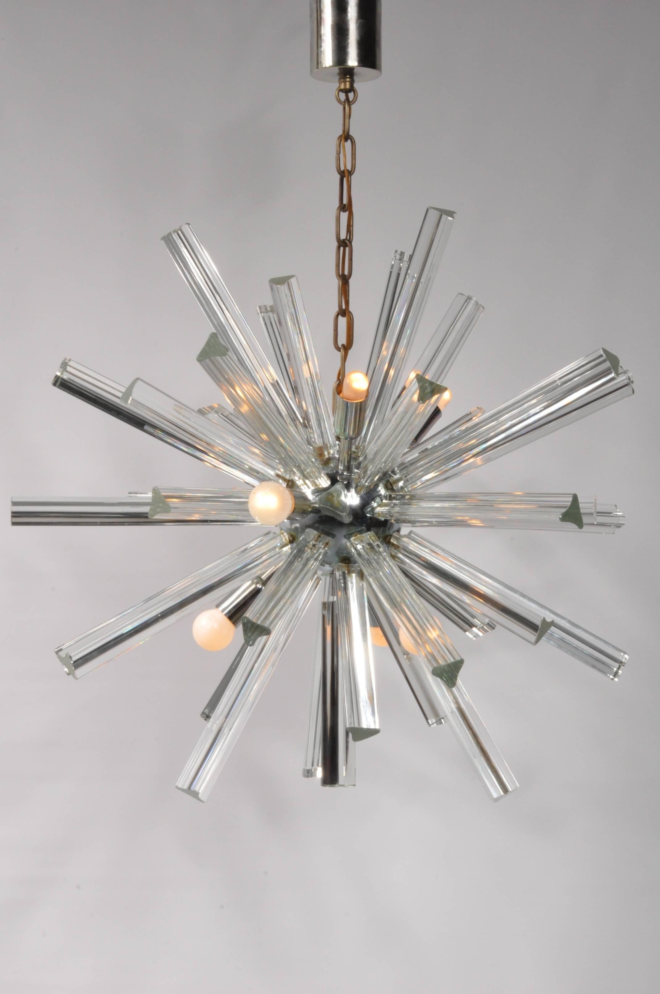 A beautiful glass chandelier manufactured by Camer Glass in Italy, circa 1970.

This impressive piece is made of a round, chrome-plated metal sphere holding many clear Murano glass prisms in different lengths. Combined with the several round light