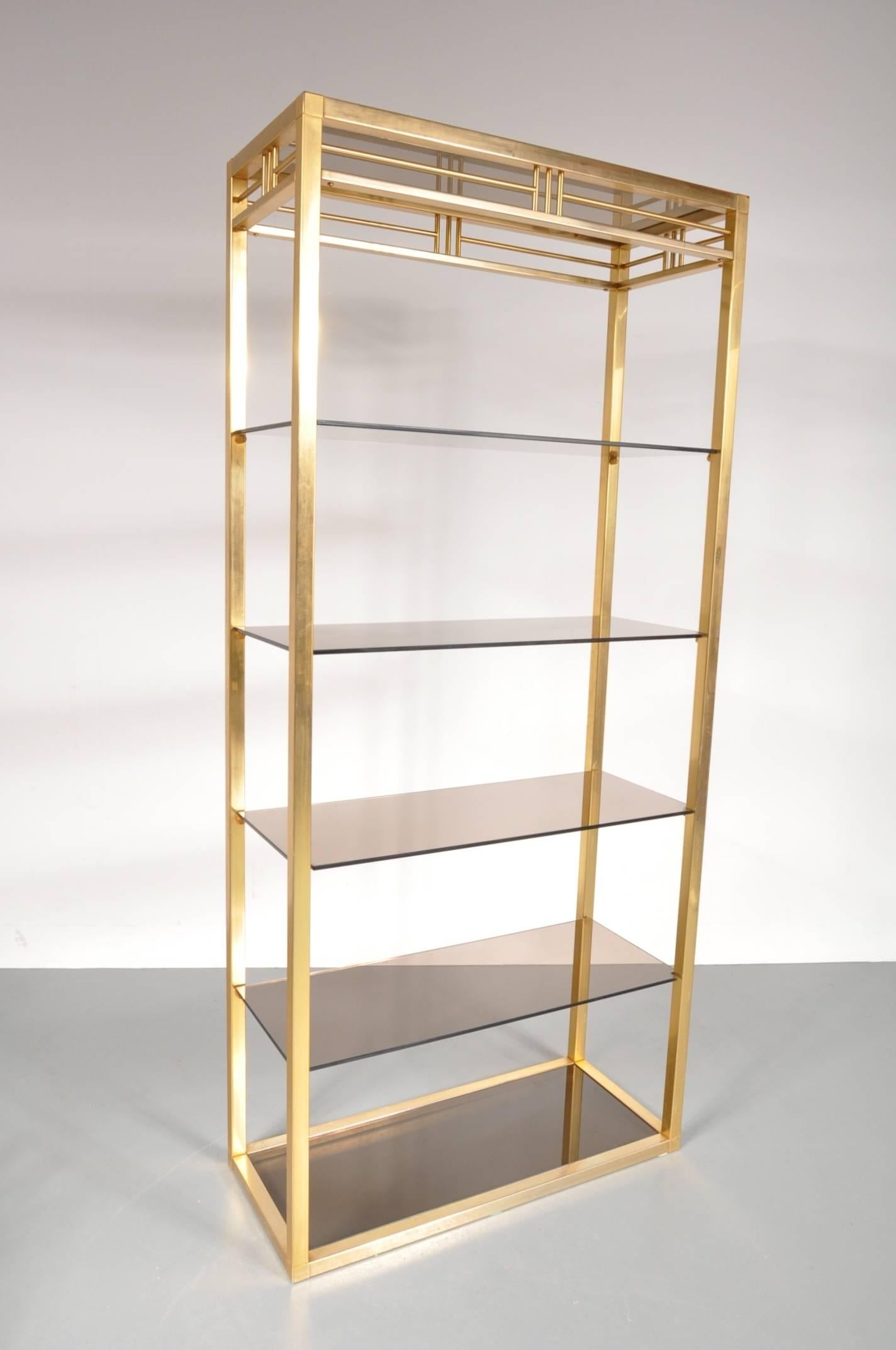 Un beau meuble, très attrayant, produit en Belgique vers 1970.

Cette pièce accrocheuse est fabriquée en laiton de haute qualité dans une belle couleur dorée, avec le verre fumé créant un style luxueux merveilleux ! Les formes droites et les détails