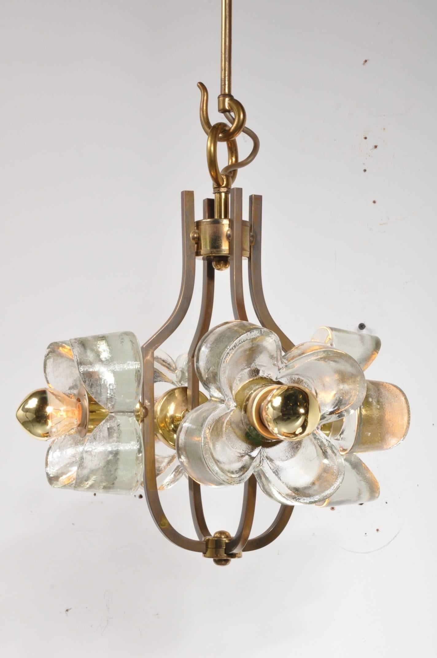 An eye-catching hanging lamp in Brutalist style, made of high quality brass with thick glass flower shapes.

The golden colour of the brass is also integrated in the bulbs within the flower shapes, creating a nice harmonious style. This lovely piece