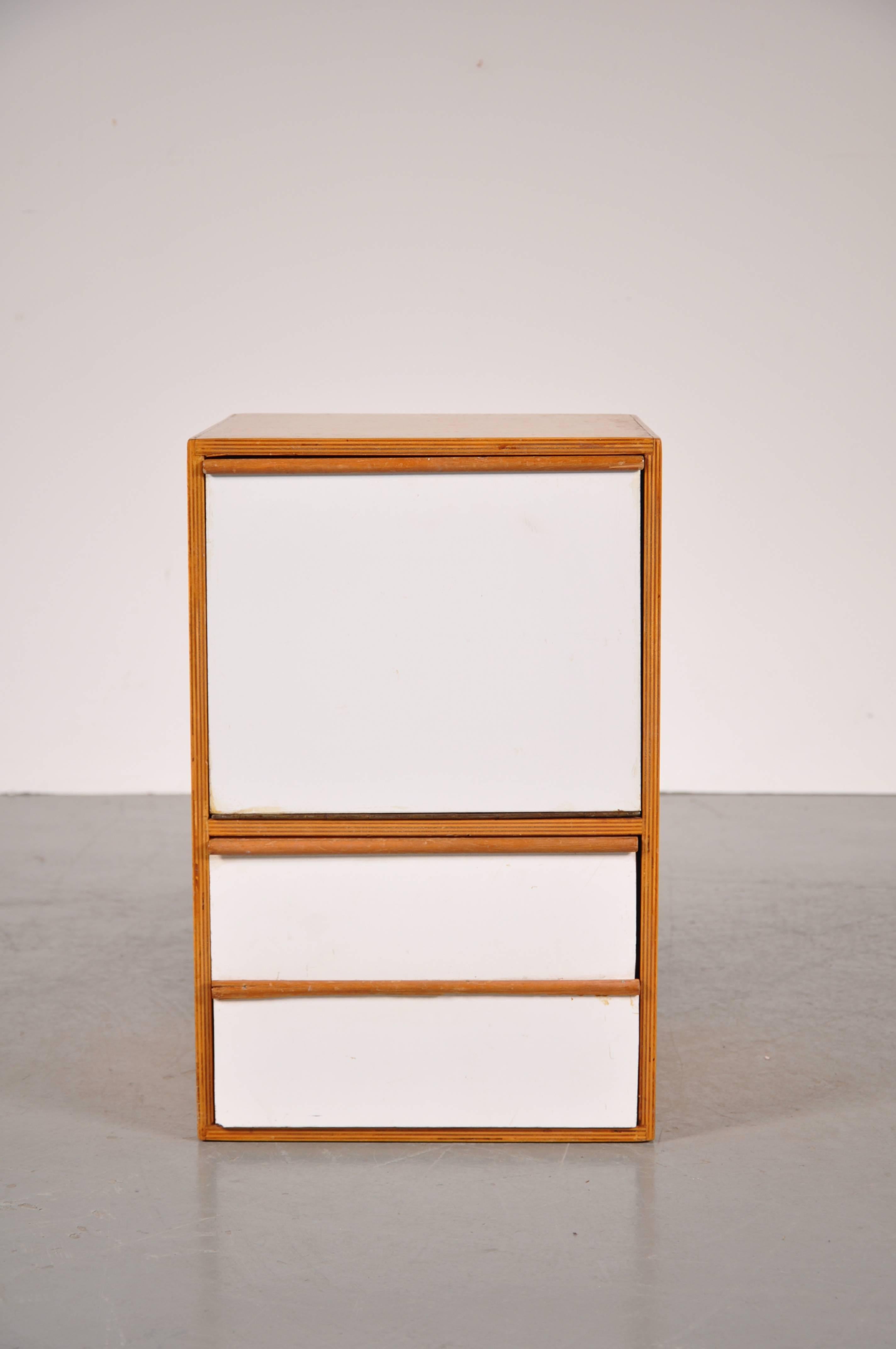 Minimalistic small Dutch cabinet attributed to Gerrit Rietveld Jr., manufactured in The Netherlands around 1950.

The cabinet has a white laminated door and two drawers. This piece comes from the same house as the four Rietveld chairs we have