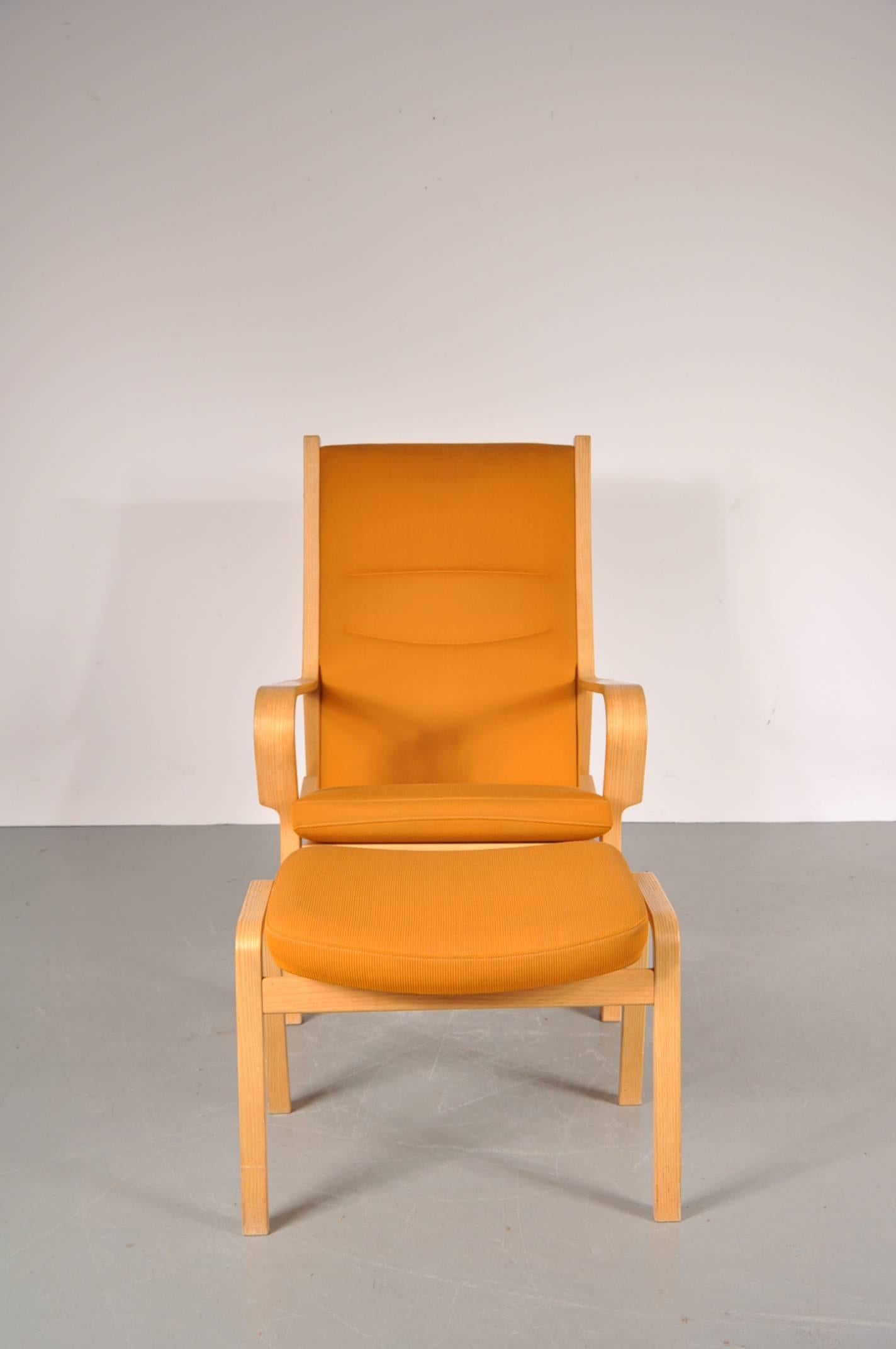 Stunning highback easy chair with matching ottoman, manufactured by Johannes Hansen in Denmark around 1980.

The set has a high quality ash with teak wooden base and original orange fabric upholstery.

In good original condition with minor wear