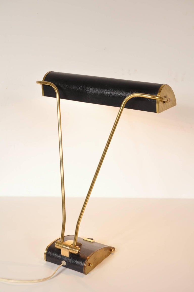 Beautiful desk lamp designed by Eileen Gray, manufactured by Jumo in France, circa 1940.

This eye-catching Art Deco lamp is made of beautiful quality brass with black metal at the base and hood. This is a rare edition with a smooth finish to the