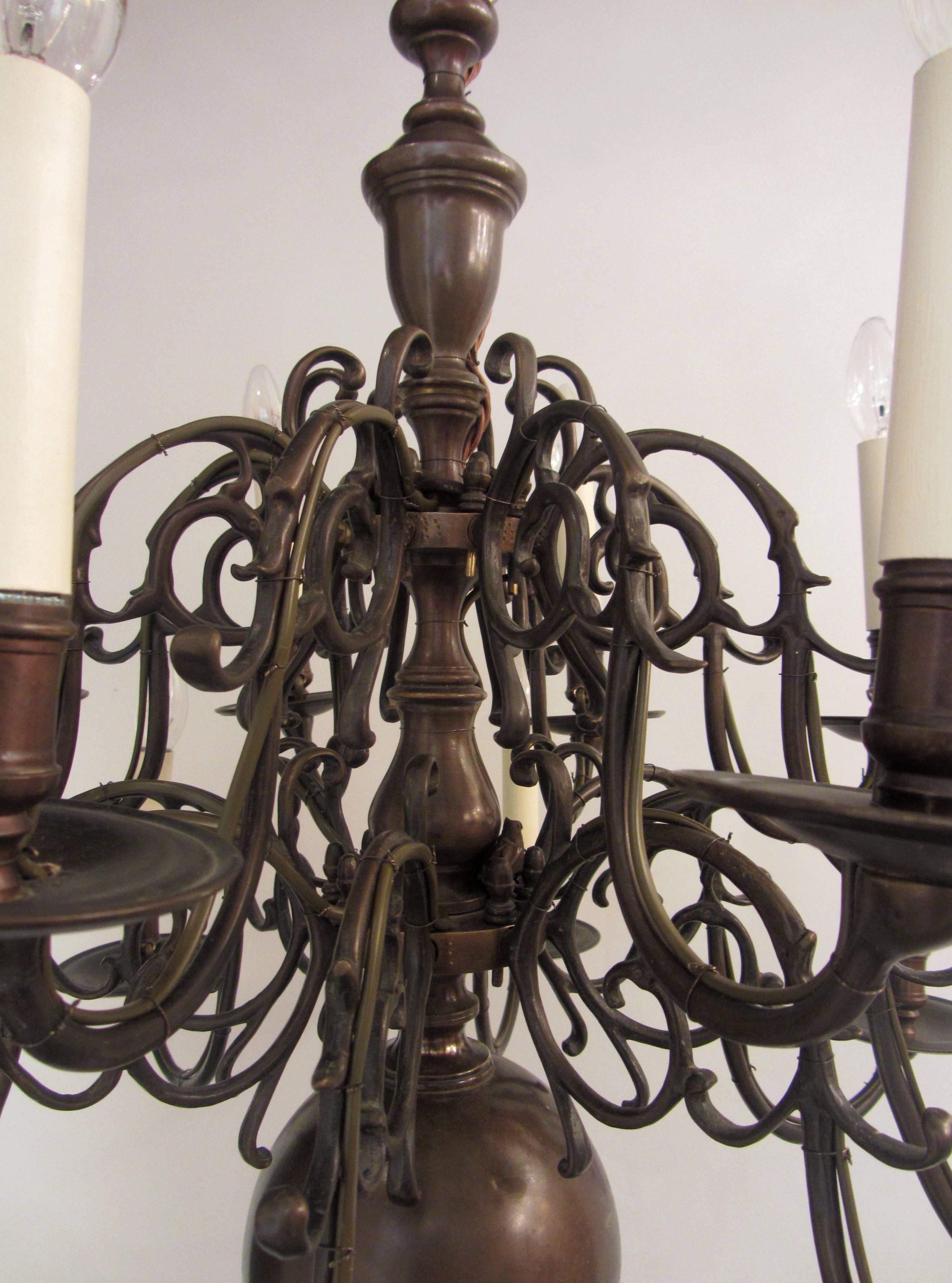 A nice quality sixteen arm, Dutch brass chandelier. The centre stem bearing two tiers of S-scroll decorative branches with candle cups on drip trays above a globe pendent. Late 19th century. Professionally wired for electricity.