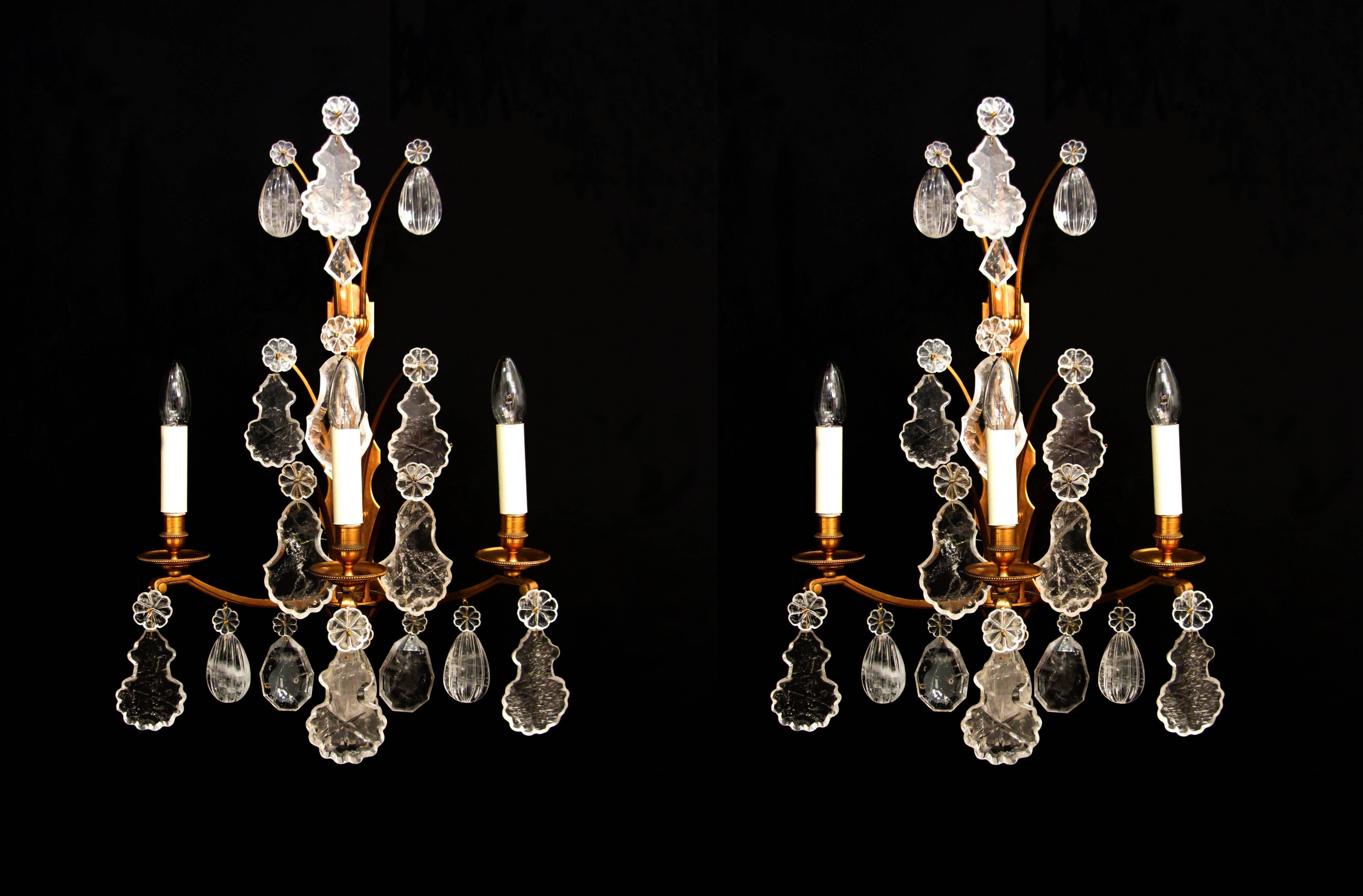 A pair of large-scale, gilt brass, three-arm wall lights, with fine rock crystal plaques and rosettes. (A similar pair is available to make a set of four).