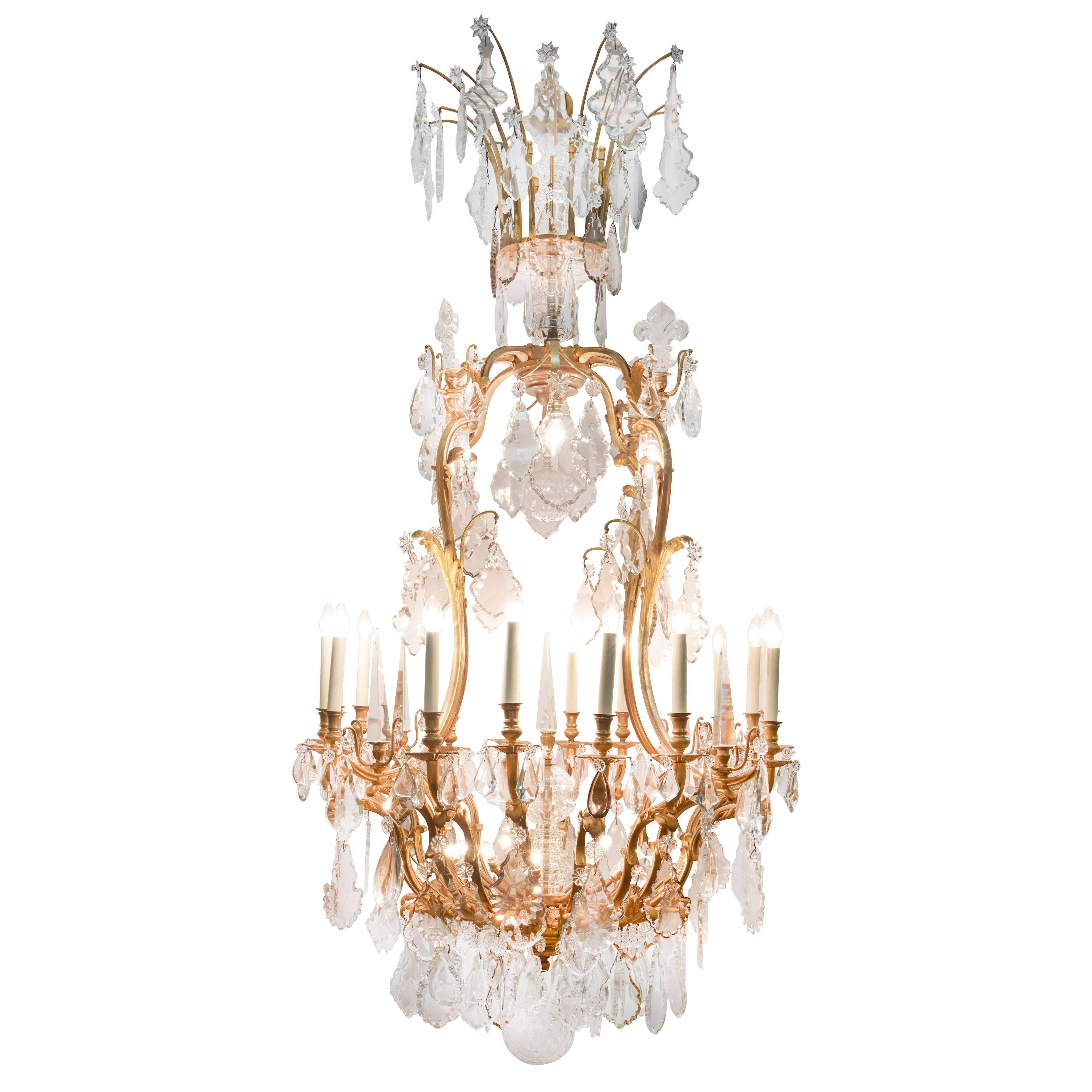 Of cartouche outline, with glass baluster shaft with acanthus scroll branches of light and spires, hung with large cut glass plaques, facetted drops and rosettes, terminated with a facetted glass ball. Professionally wired for