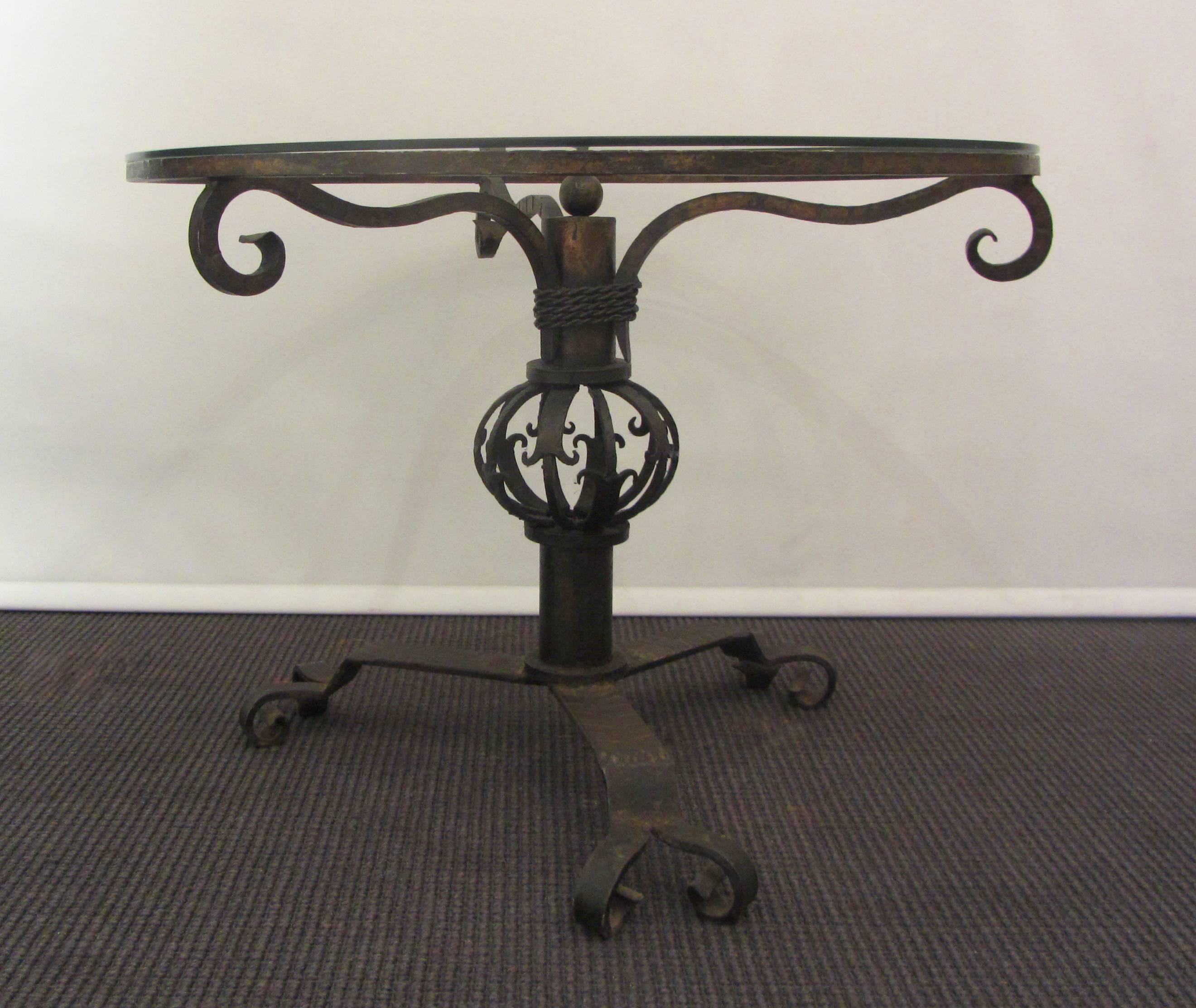 An unusual hand-forged wrought iron coffee table base with a circular glass top. The glass is 1/4 inch thick.
