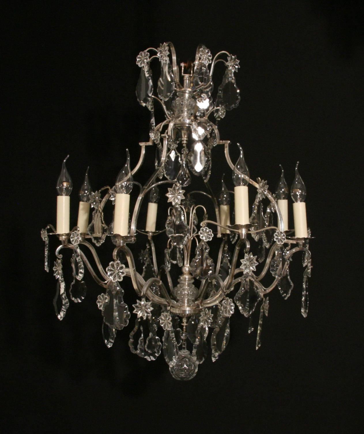 A well-proportioned, silvered bronze, birdcage form eight-arm chandelier, profusely hung with crystal plaques and rosettes.