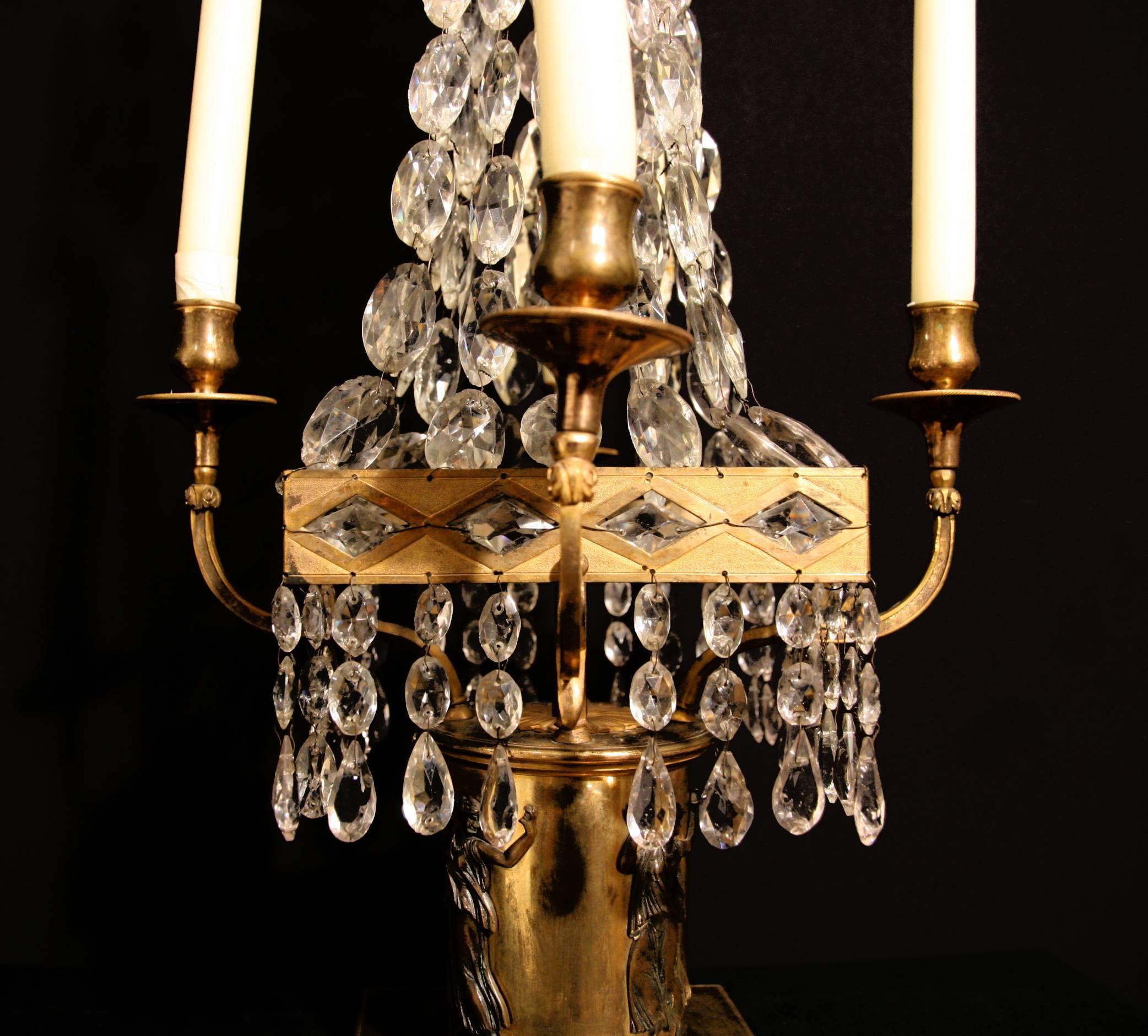 A pair of Baltic gilt-bronze and crystal glass, empire style, four branch candelabra, the plinth decorated with classical figures.
