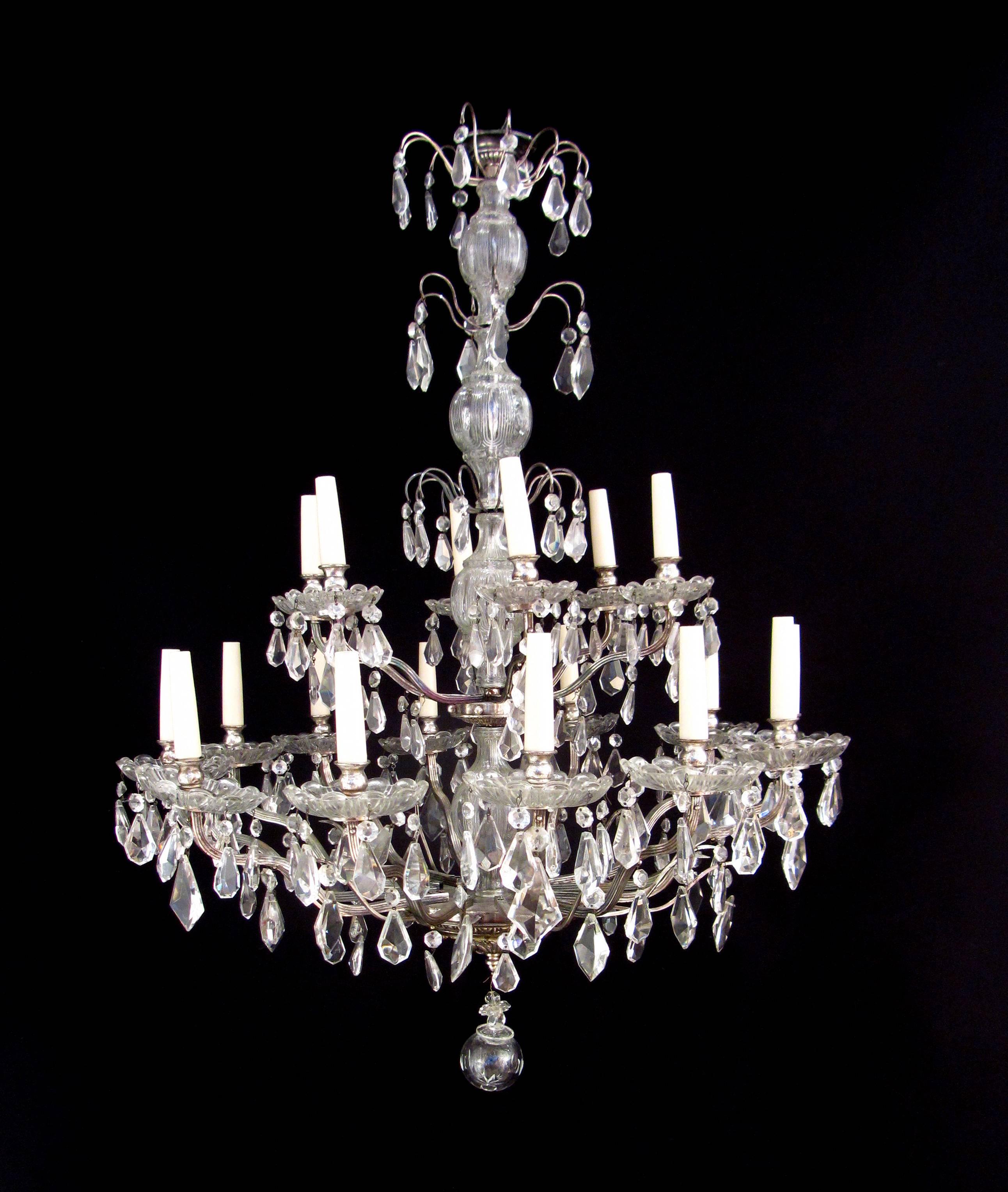 A pair of silvered brass and crystal chandeliers. The handblown glass encased stem supports splays of crystal drops and eighteen arms of light over two tiers, French, circa 1880.