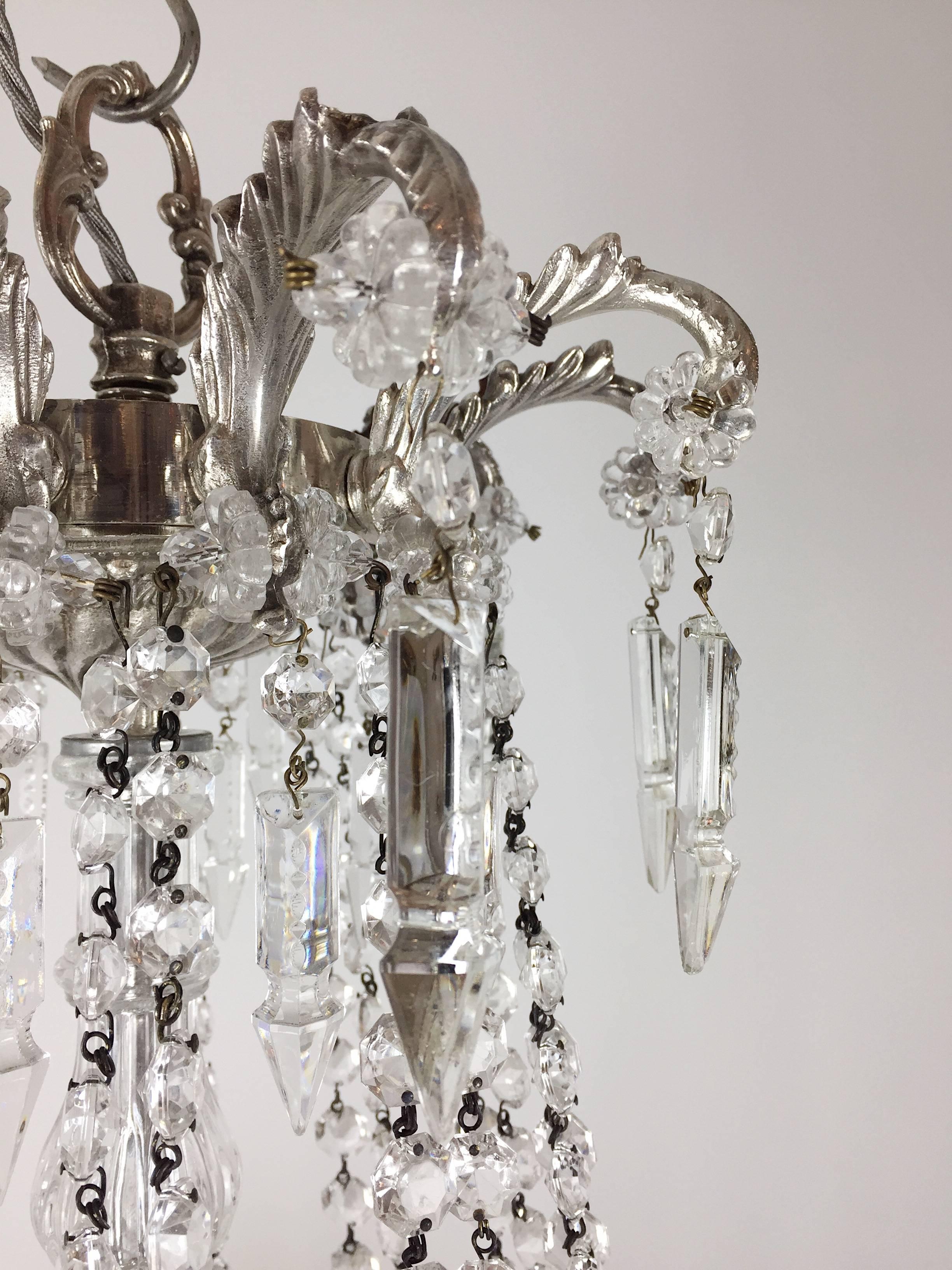 A pair of late 19th century silvered brass bag and swag chandeliers, possibly Spanish, hung with hand-cut faceted buttons and icicle drops.