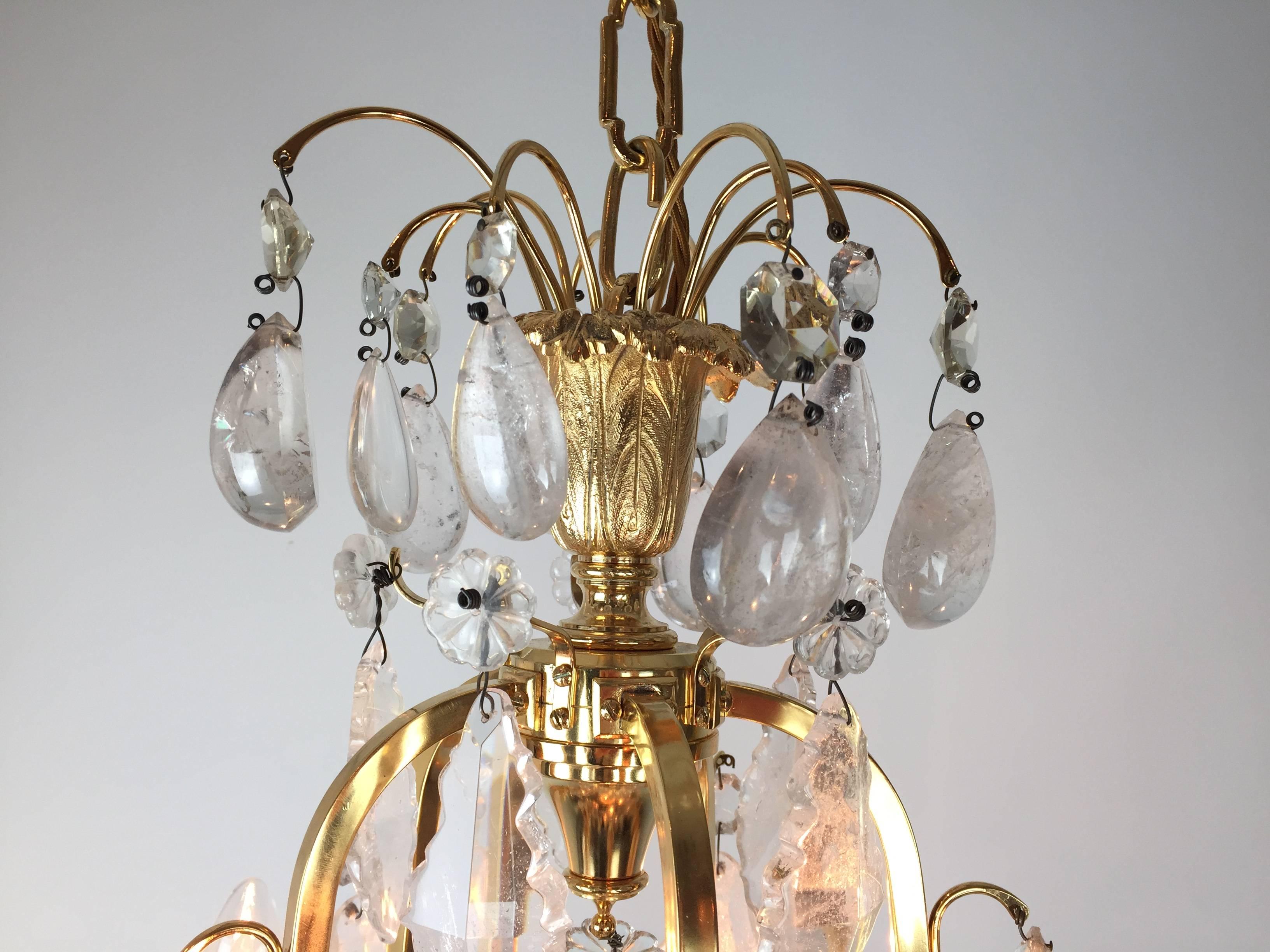 A pair of French 22-carat gold-plated and rock crystal adorned chandeliers with faceted cut crystals. The cast and chiselled drip pans supported on outward swept arms now electrified and internally lit, all of superb quality.