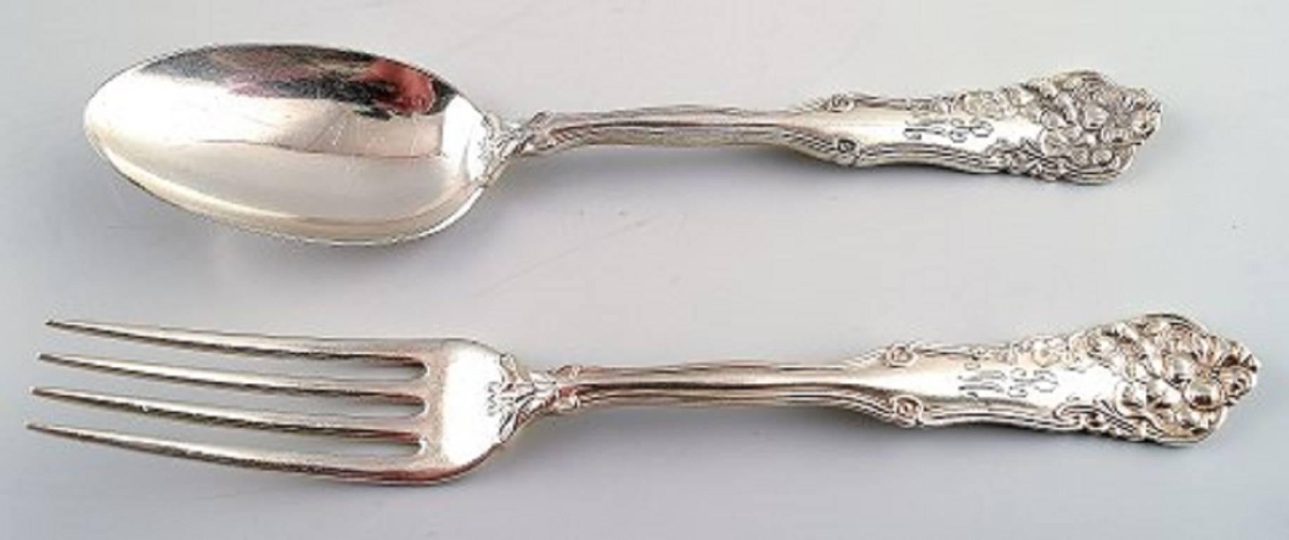 13 pieces American silver, Wallace sterling and W. Rogers, with rich ornamentation.

Consisting of seven spoons, four forks, bottle opener and a large fork.

Stamped.

The large fork measures 20 cm.

In good condition, some pieces with engravings.