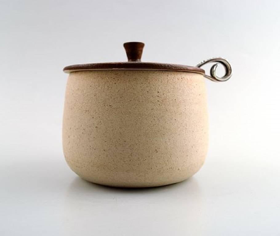 Arne Bang, pottery jam jar with Danish sterling silver spoon,

Denmark, mid-20th century.

Hallmarked.

Glaze in sand and brown tones.

In perfect condition.

Measures: 9 x 9 cm.