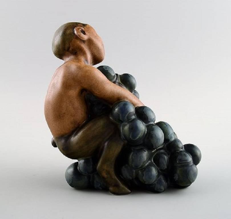 Bing & Grondahl stoneware figurine of small Bacchus with bunch of grapes by Kai Nielsen (1882–1924).

Model number 4027. 

From the series 'Grape Harvesting'.

Measures 11 cm. x 11 cm.

1. Quality, in perfect condition.