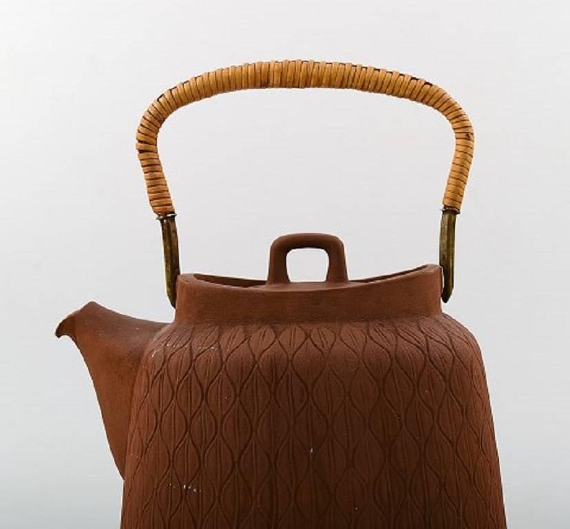 Jens Quistgaard: Teapot in fired chamotte clay with handle of cane.

Stamped Palshus, Denmark, JHQ. 1950.

Measures: Height 22 cm, diameter 18 cm.

In good condition. Ordinary wear.