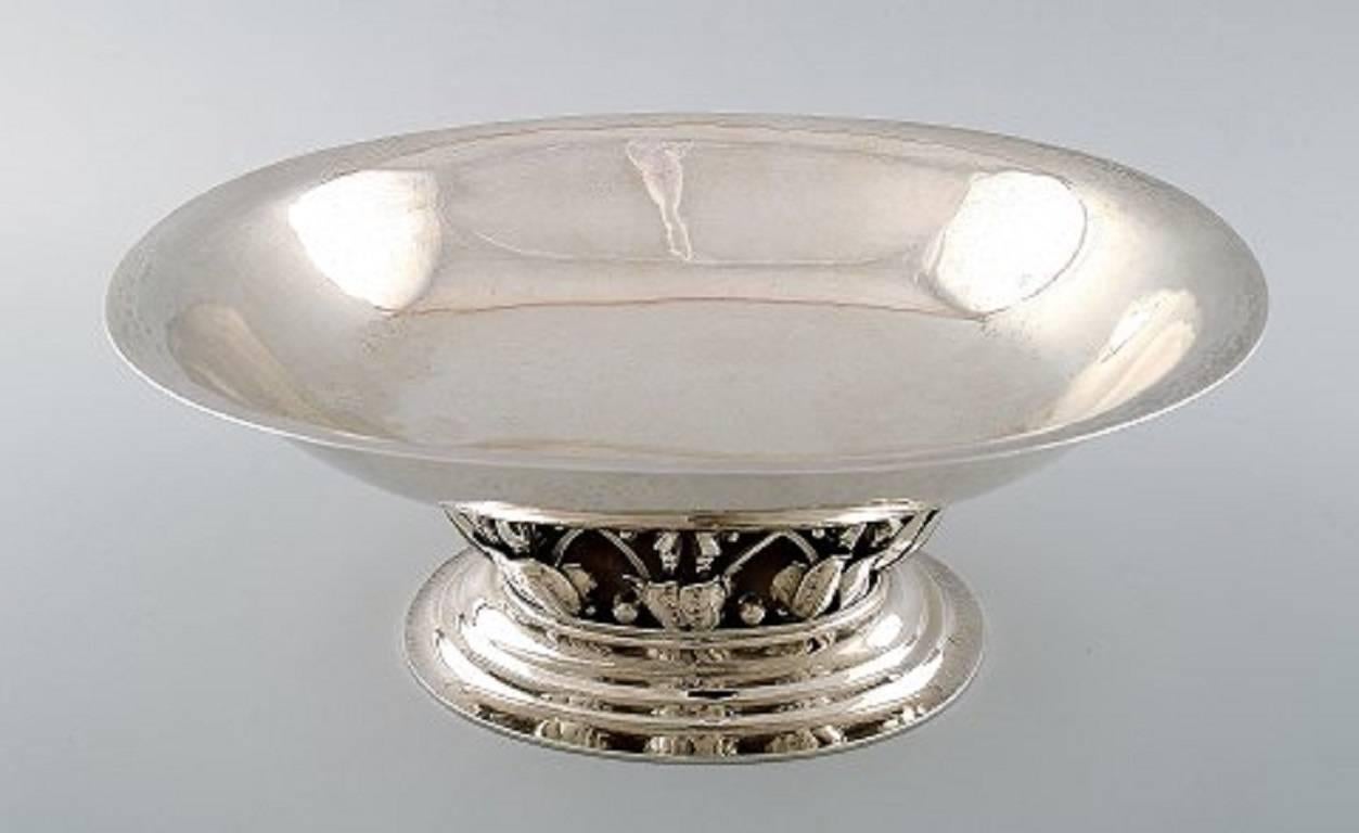 Georg Jensen, b. Rådvad 1866, d. Hellerup 1935.

Oval, hammered sterling silver centrepiece. Enchased with leaves in relief. 

Georg Jensen anno 1920. 

Design no. 306 B. Weight 906 gr.

Measures: Length 27.5 cm, height 11.5. cm.

In