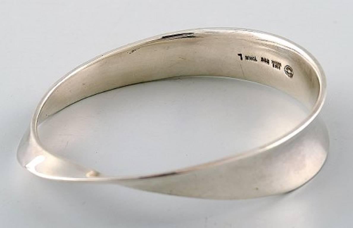 Georg Jensen bracelet - Vivianna Torun Bülow-Hübe.

Sterling silver. Designed 1968.

Stamped TORUN, Georg Jensen. Model no. 206.

Interior dimensions 7cm. x 5.5 cm. Size Large. 51.7 grams.

In perfect condition.