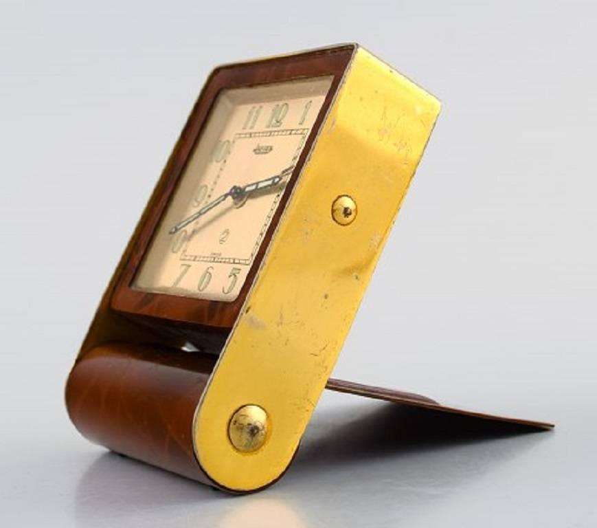 Art Deco travel alarm clock, tortoiseshell and brass, Jaeger (LeCoultre), circa 1930. 

Gold-colored dial with clockwork, flap lid with setup mode.

Measures: H 8.5 cm, W 5.5 cm, D 2.5 cm.

In very good condition, the clockwork works.