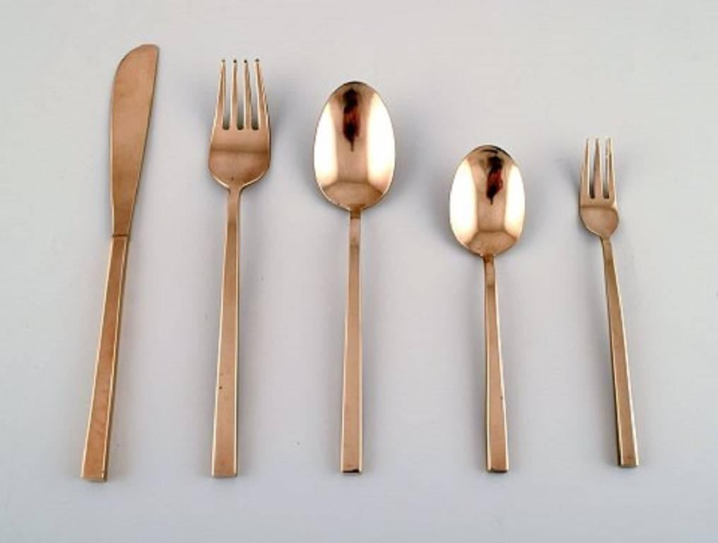 Sigvard Bernadotte 'Scanline' cutlery in brass complete for four people. 

Consisting of: Four dinner knives, four dinner forks, four soup / dessert spoons, four cake forks, four tea spoons / ice cream spoons and a large serving spoon.

In very good